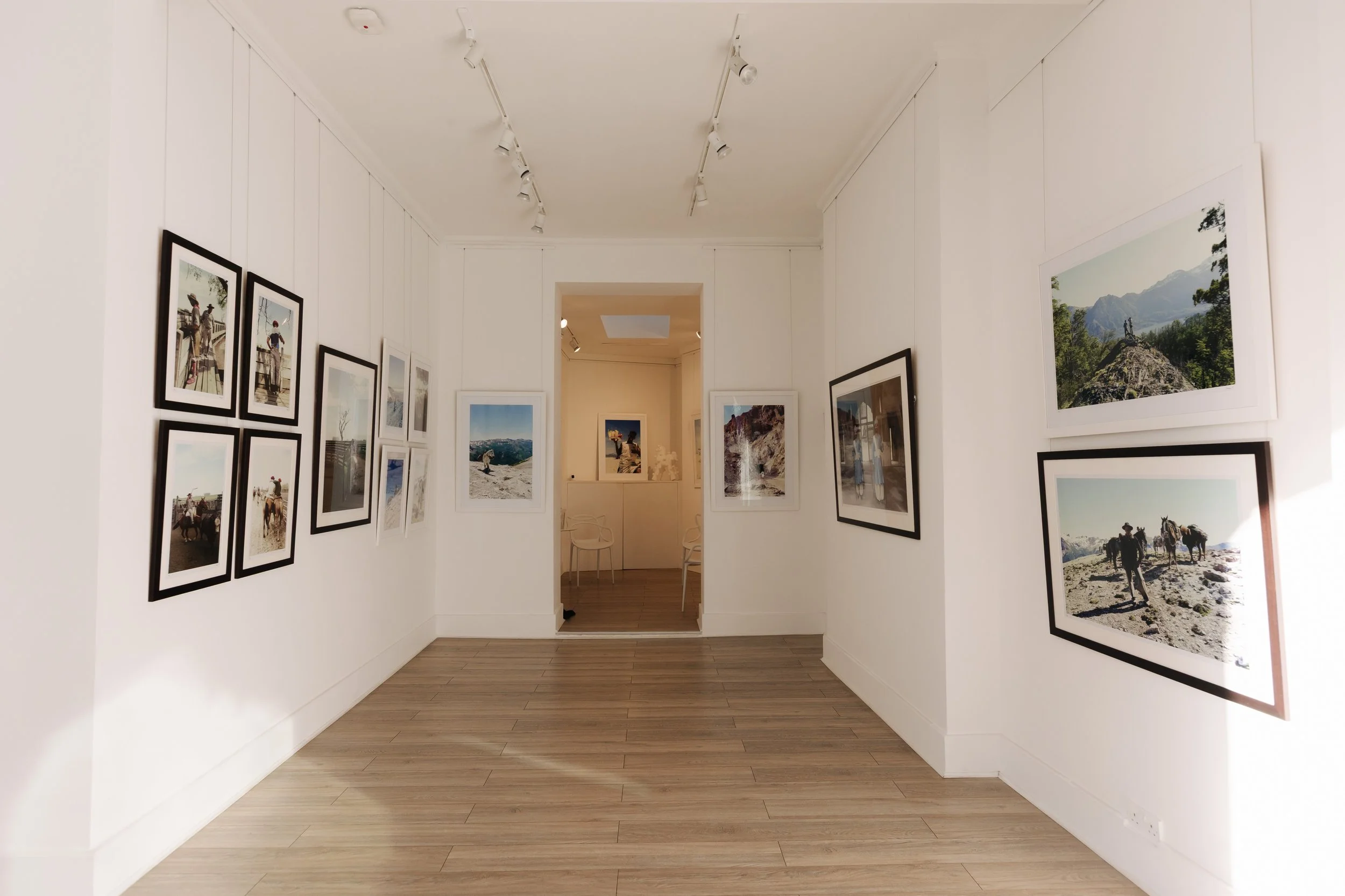 Art gallery with framed photographs of outdoor scenes and mountaineers, white walls, wooden floor, and ceiling-mounted track lighting.
BELONGING , sabaya verger first exhibition