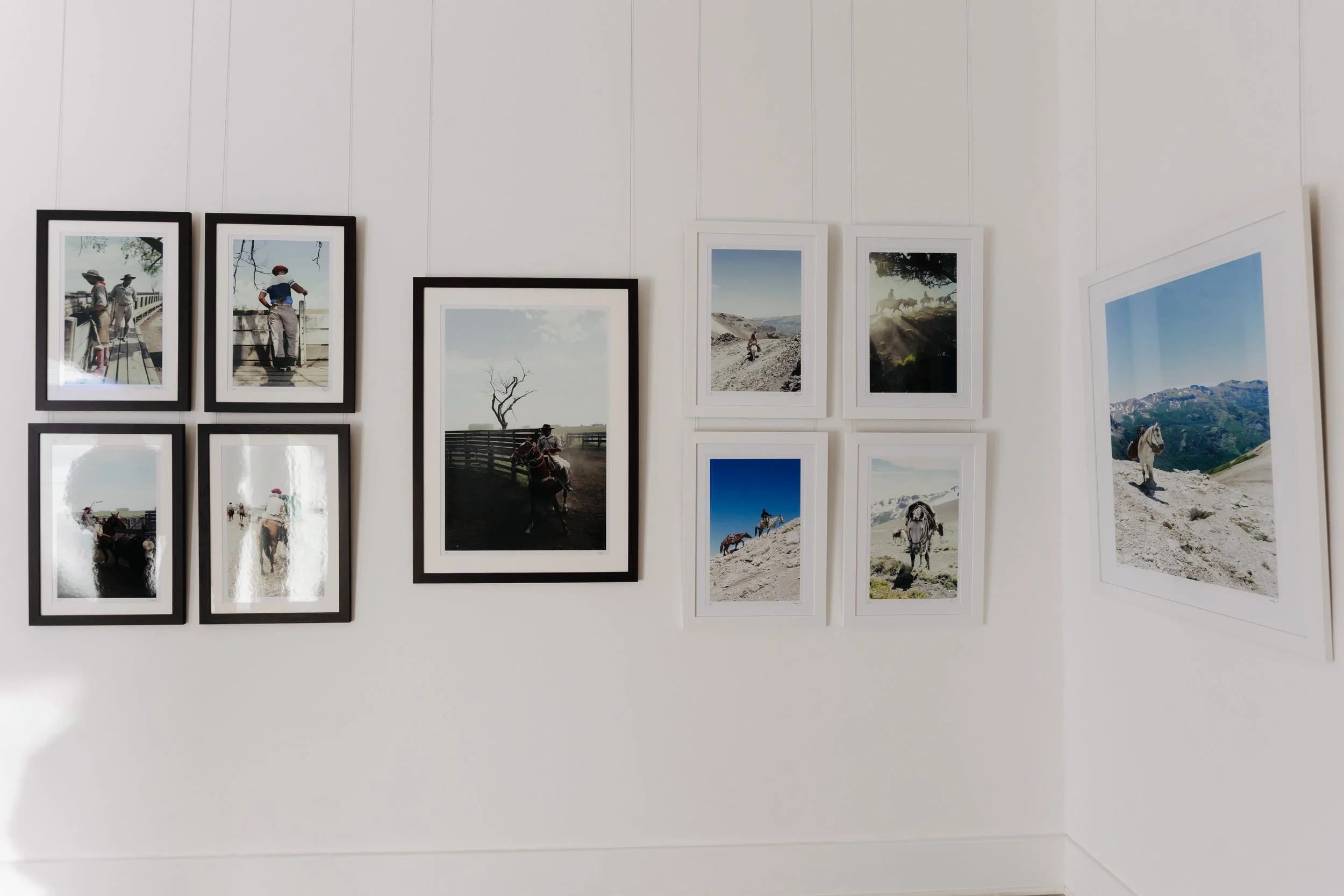 Gallery wall with framed landscape and nature photographs, including scenes of horses, mountains, and desert landscapes. bELONGING, sabaya verger first exhibition
