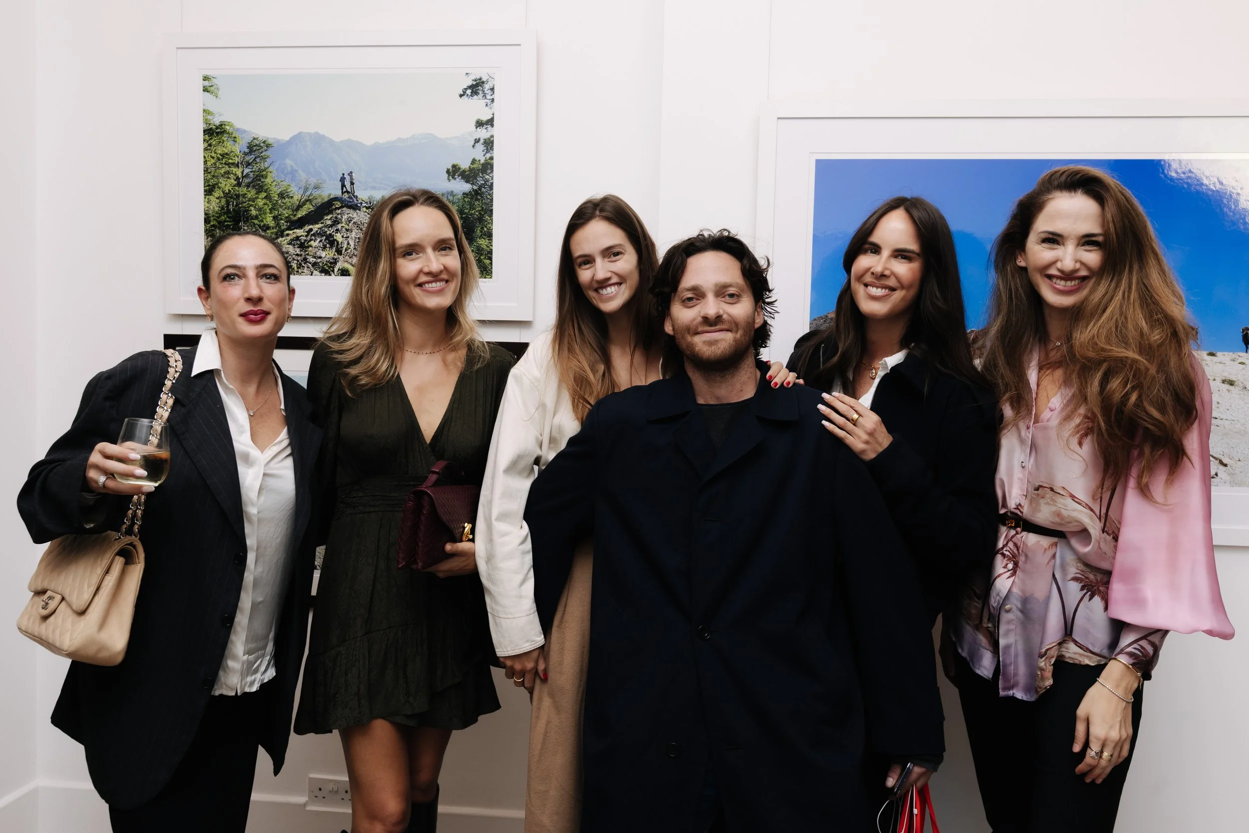 Group of six people posing in front of framed landscape photographs at an art gallery. Isabel Engels, Lavinia Roma, Nicolas sorbac, Marie jOSE Gallery and charlotte laborde. Belonging - sabaya verger