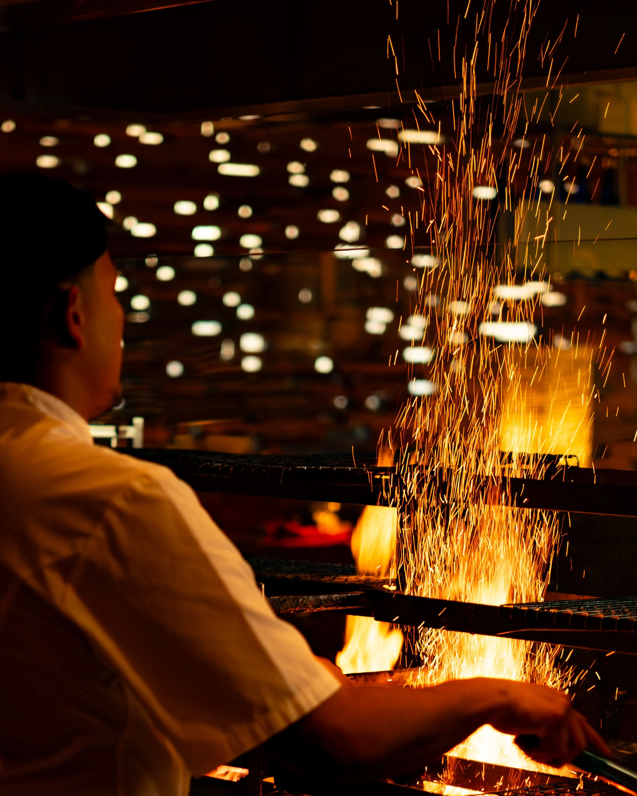 A person welding metal, with sparks flying in the dark.