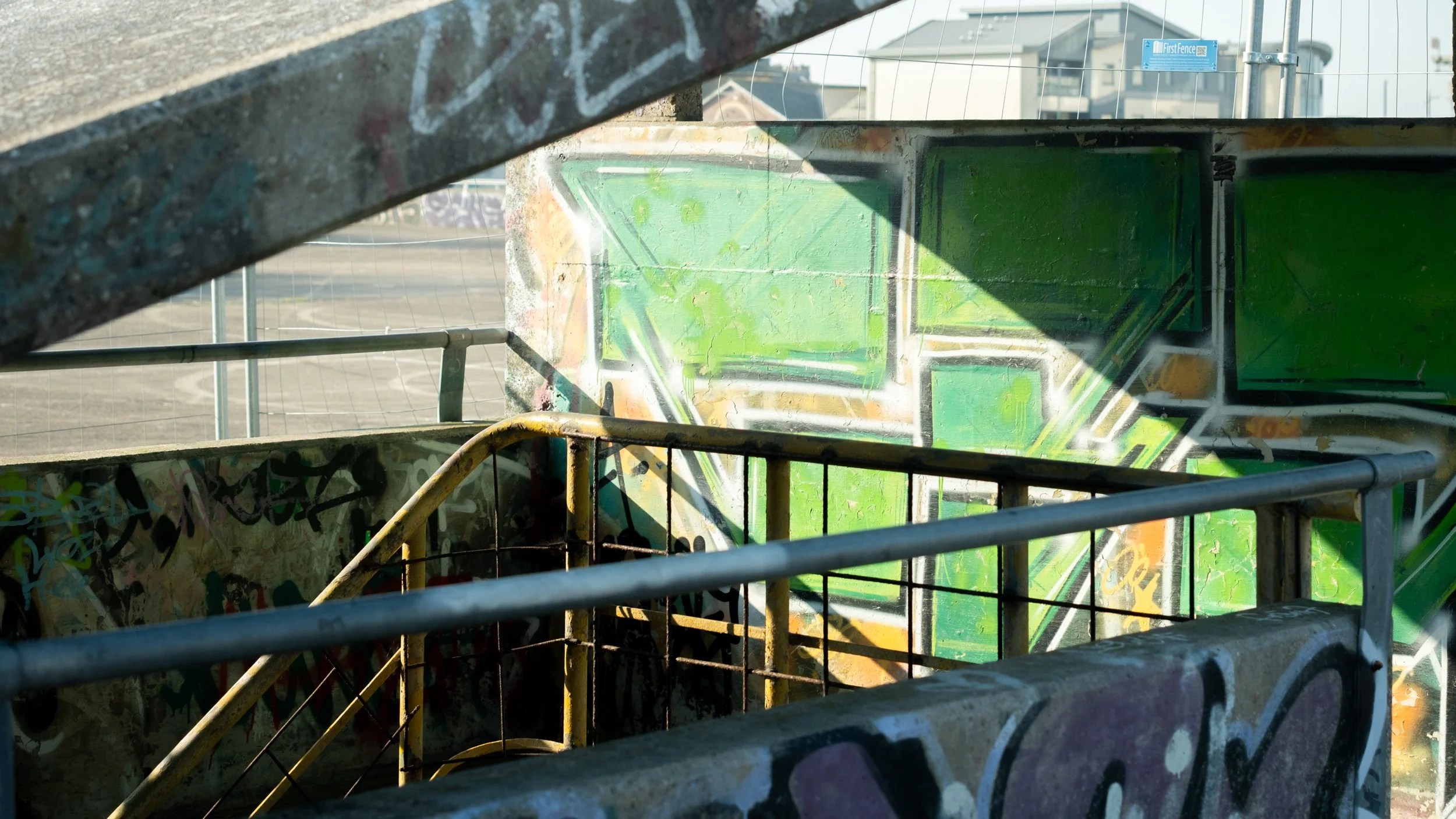 Graffiti-covered skate ramp seen through a metal fence.