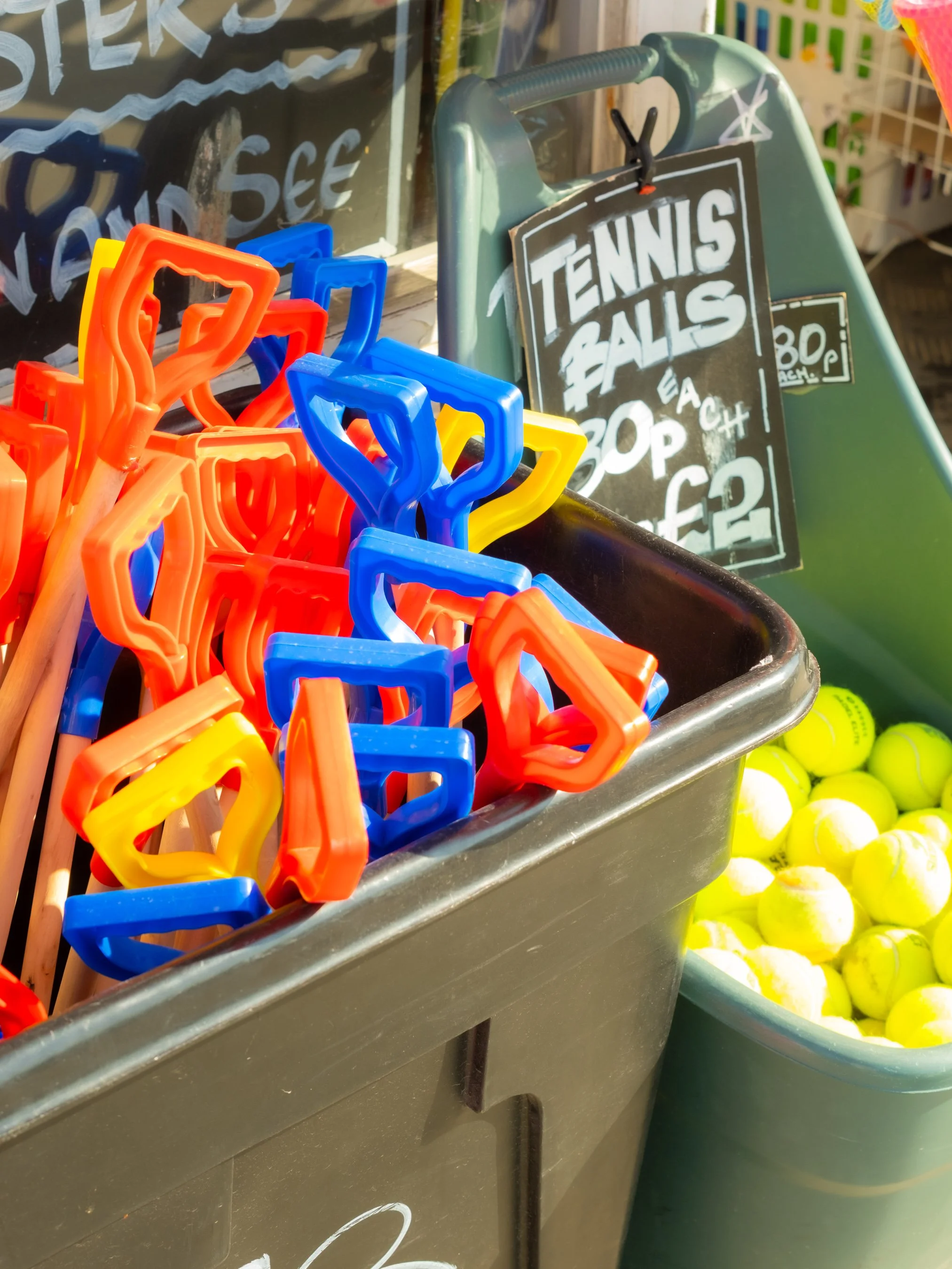 Colorful plastic tennis ball holders and tennis balls in a metal container.