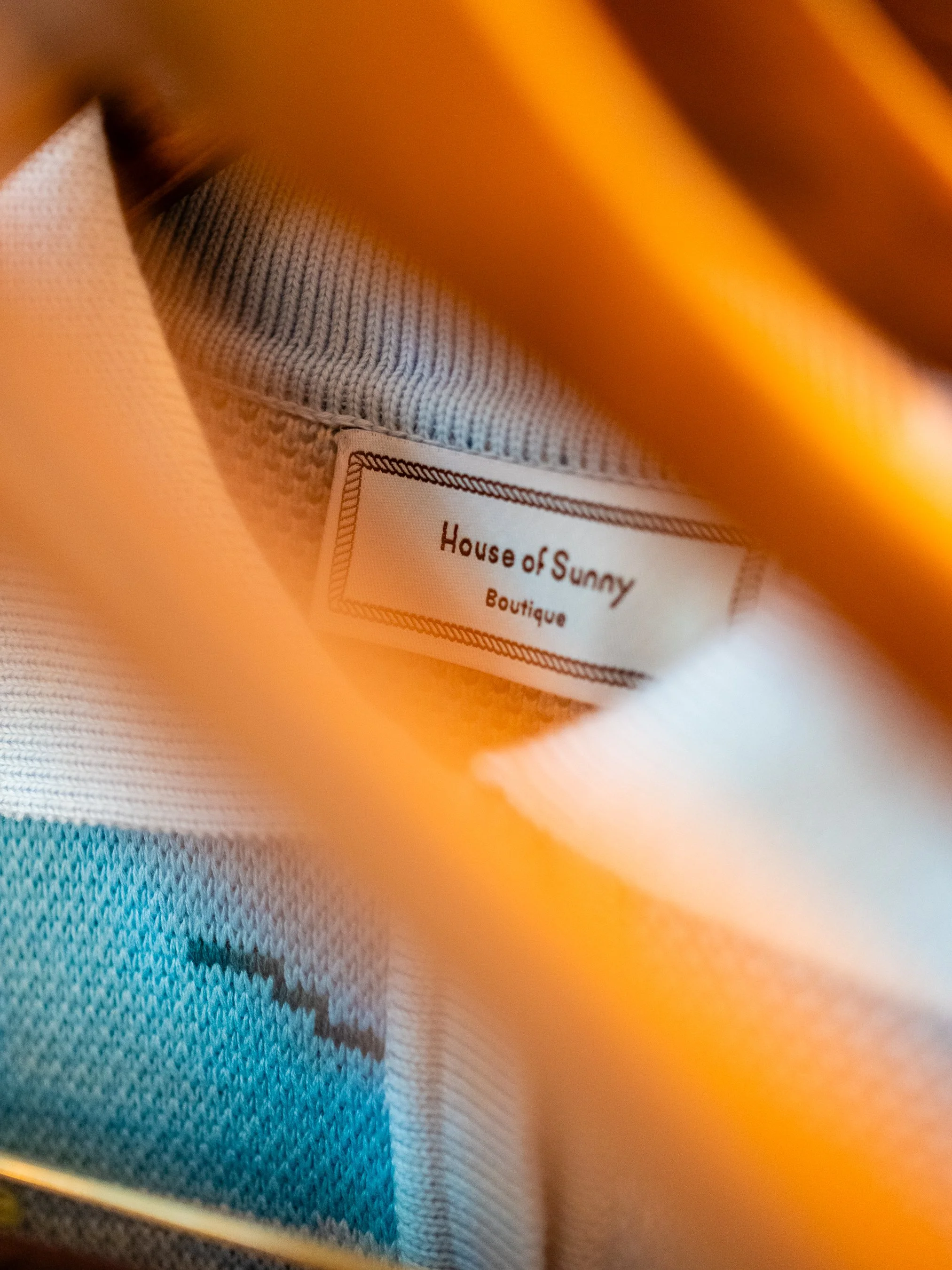 Close-up of a clothing label inside a white garment with the brand name 'House of Sunny' and the word 'Boutique' visible.