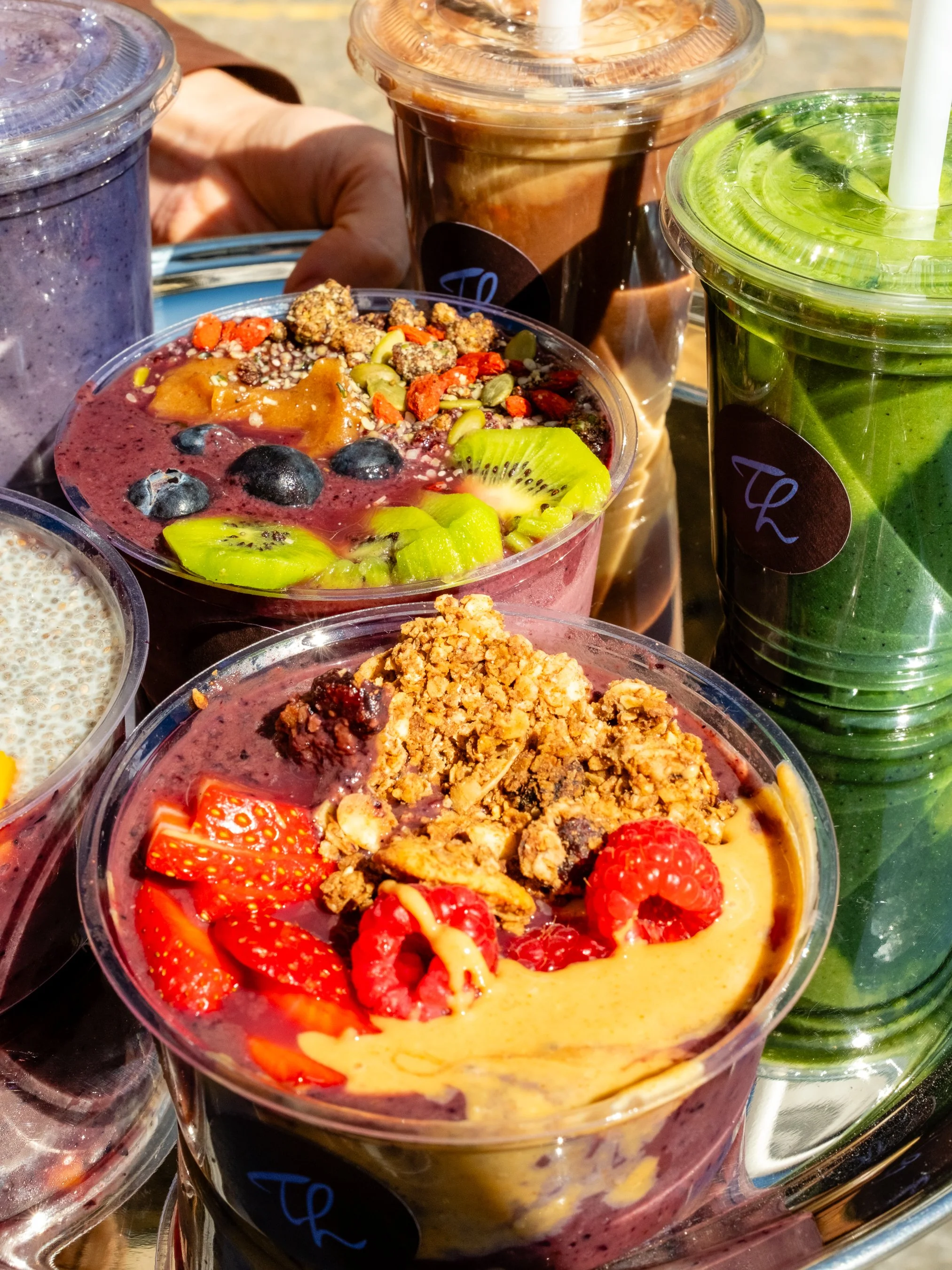 Assorted colorful smoothies topped with fresh fruits and granola.