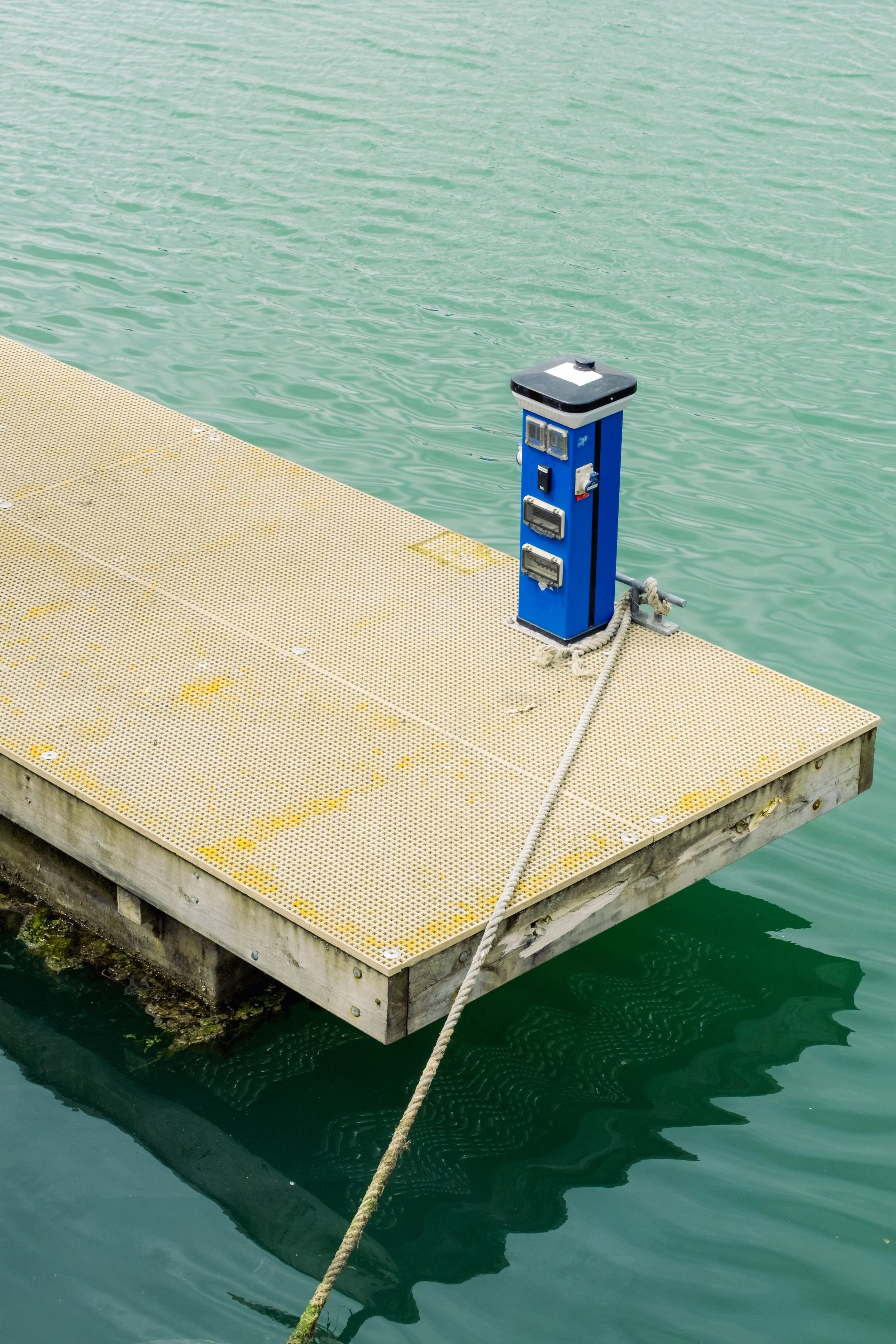 A floating dock with a blue electrical pedestal on the water.