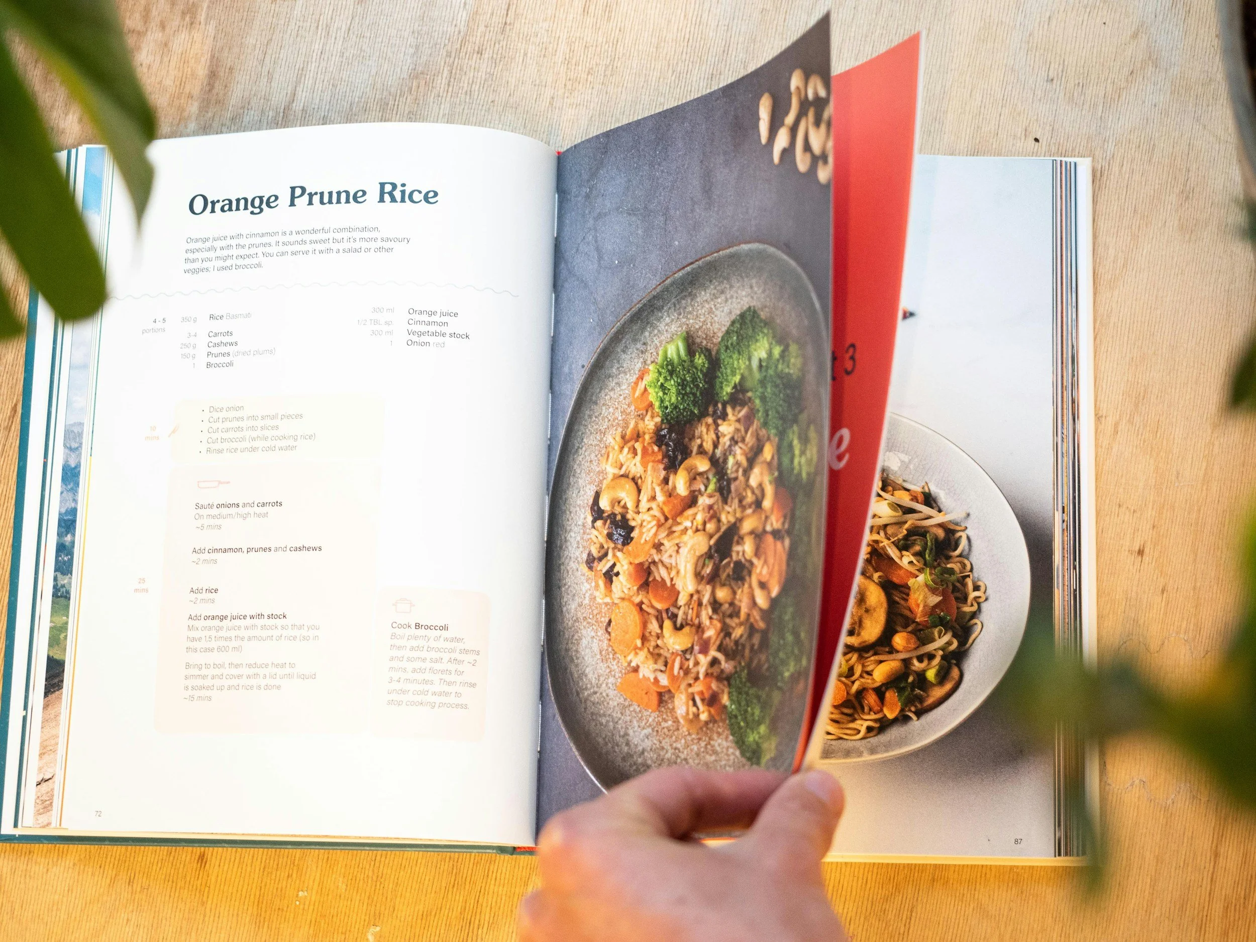 Open cookbook showing a recipe for Orange Prune Rice and a picture of the finished dish featuring rice, broccoli, carrots, and other vegetables.