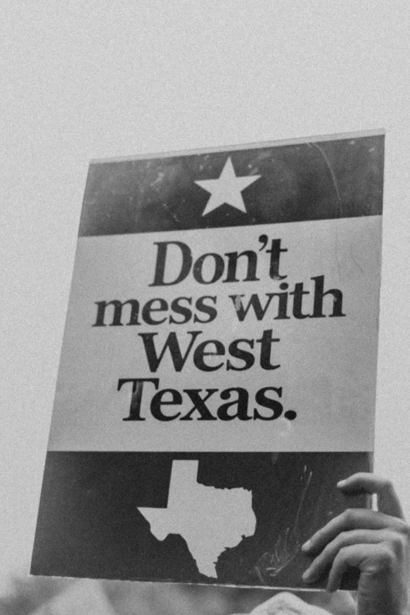 A protest sign with the Texas flag at the top, the message 'Don't mess with West Texas' in bold text, and an outline of the state of Texas at the bottom.