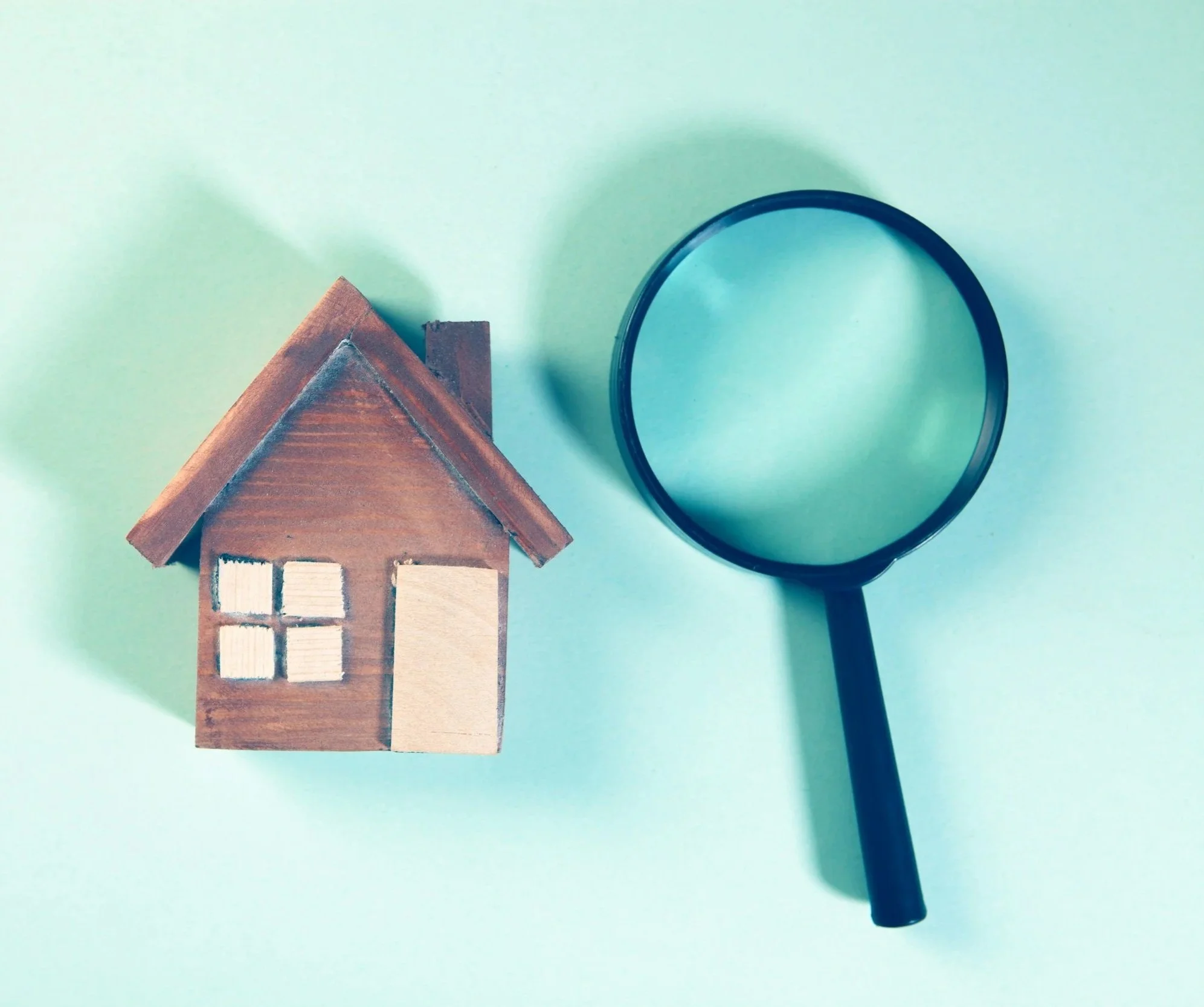 County Property Advisors will find the right solution for your property. Wooden house model beside a magnifying glass on a turquoise background