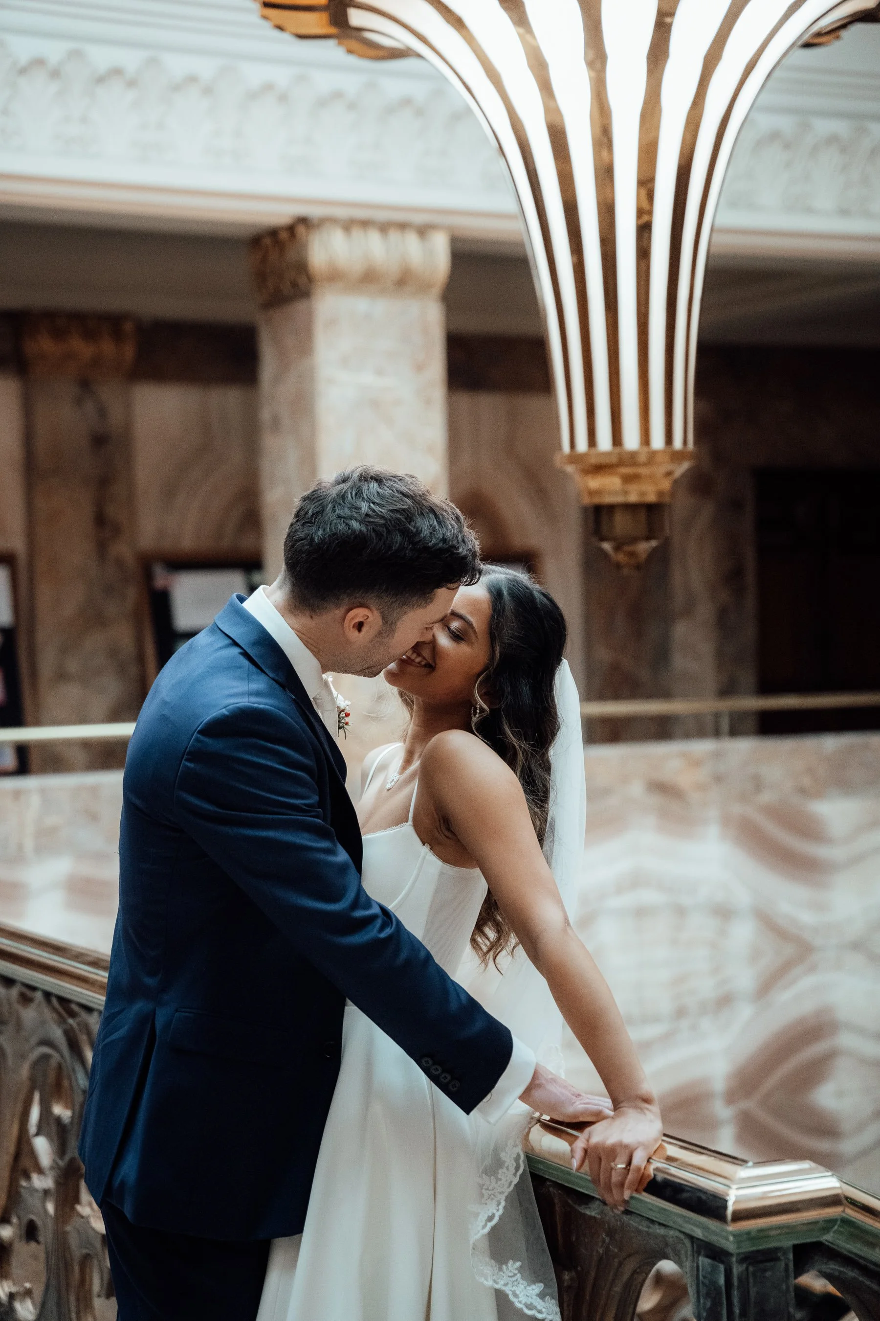 A bride and groom sharing an intimate moment on their wedding day inside a church with ornate columns and arches.