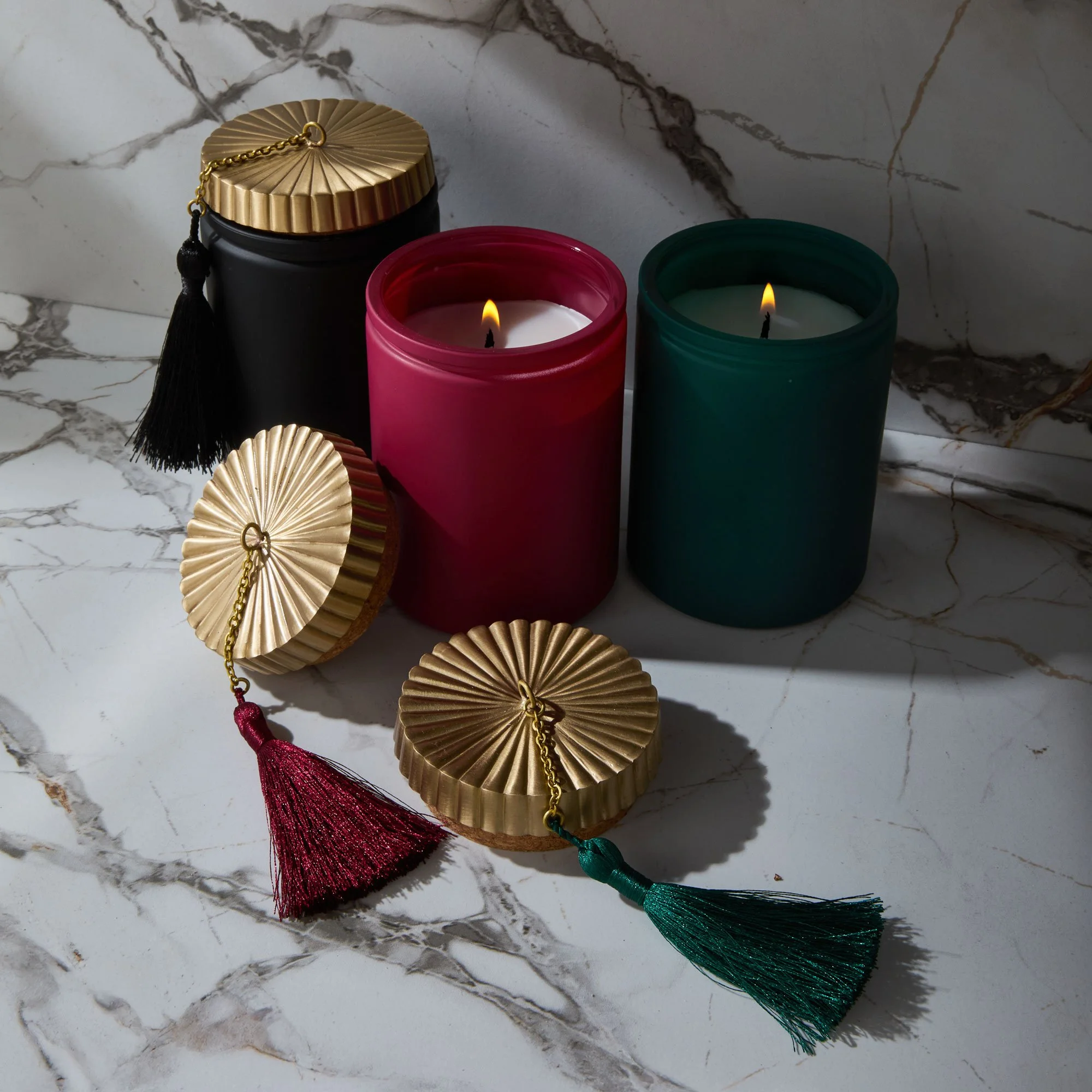 Decorative Tassels with metallic caps and tassels in red, green, and gold colors on a marble surface.