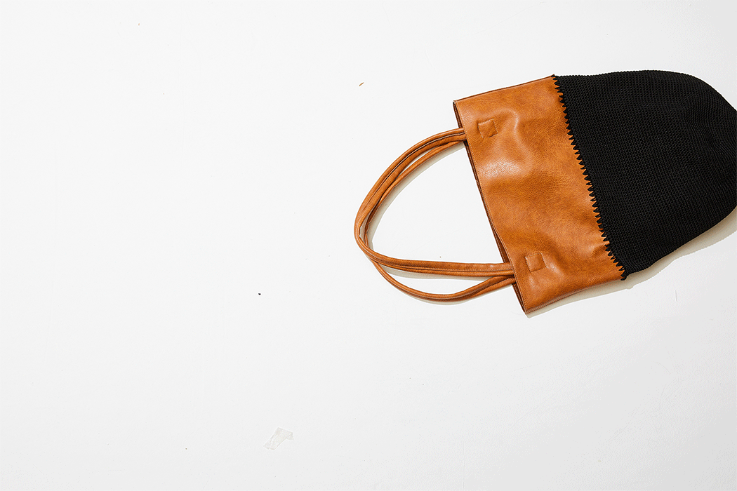 Brown tote bag with black knitted fabric on a white surface