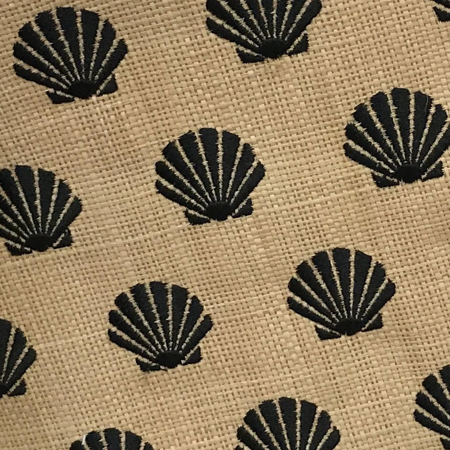 Pattern of black embroidered scallop shells on beige fabric.