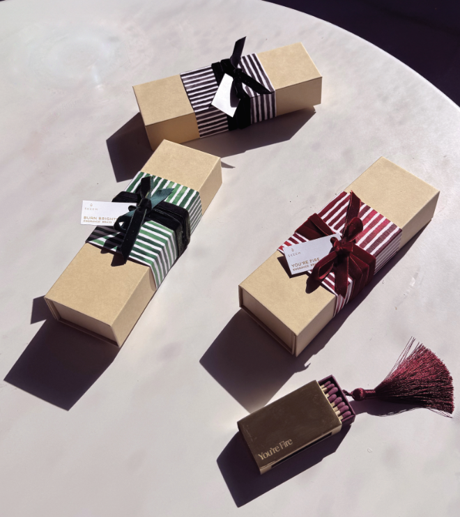 Three rectangular gift boxes with striped wrapping paper and ribbons, and a small rectangular box with a tassel, on a white surface.