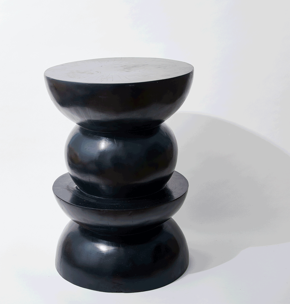 A black, glossy, abstract sculpture with multiple rounded, disc-like shapes stacked vertically, set against a white background.