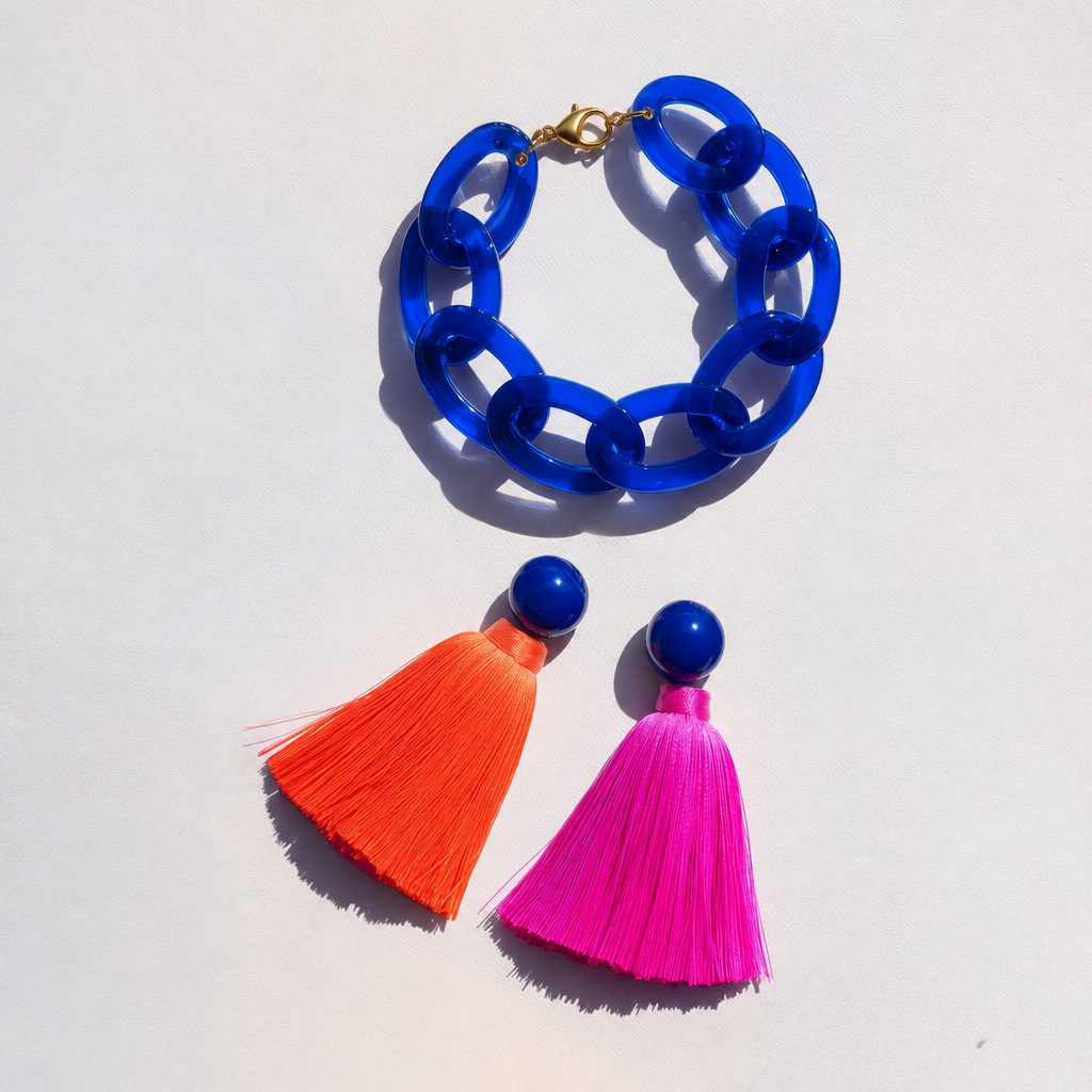 Blue chunky chain necklace with gold clasp and two colorful tassel earrings on a white background.