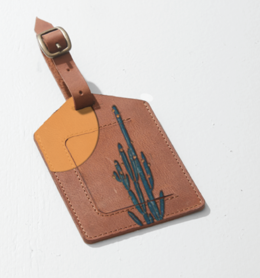 Leather luggage tag with a cactus design and a yellow semi-circle accent, attached to a brown strap with a silver buckle.