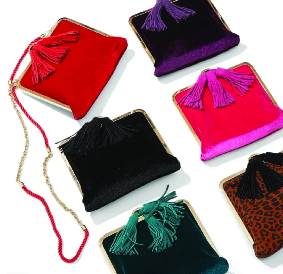 Six colorful small clutch purses with tassels, arranged on a white surface. The purses are in red, purple, pink, black, green, and leopard print designs.