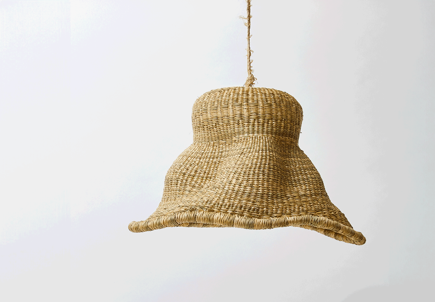 A woven rattan pendant light with a bell-shaped shade hanging from a rope cord against a plain white background.
