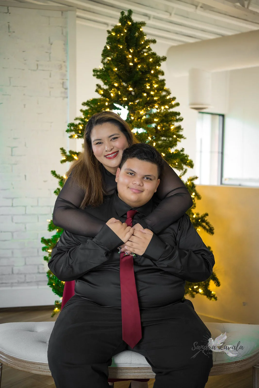 Sandra hugging her son in front of their Christmas tree.