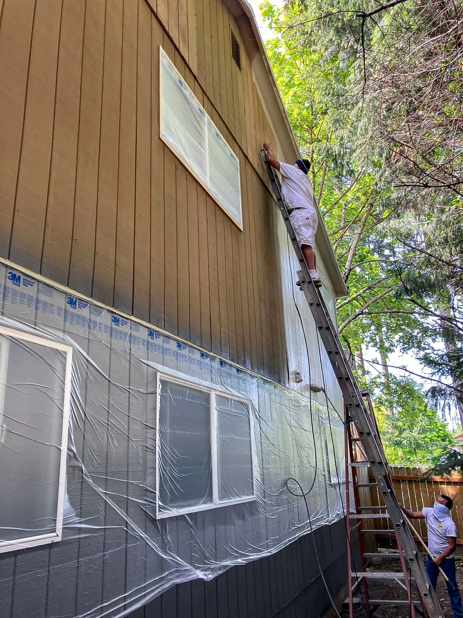 A person on a ladder working on the side of a house.