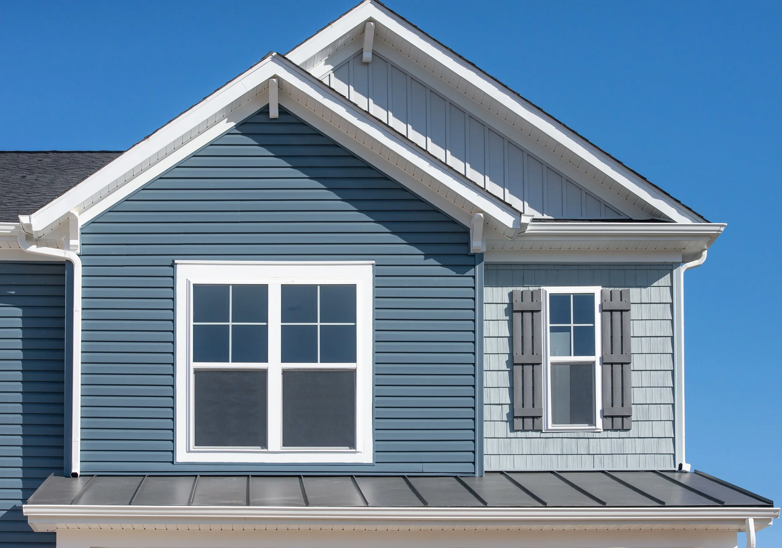 The siding of a blue house with white trim.