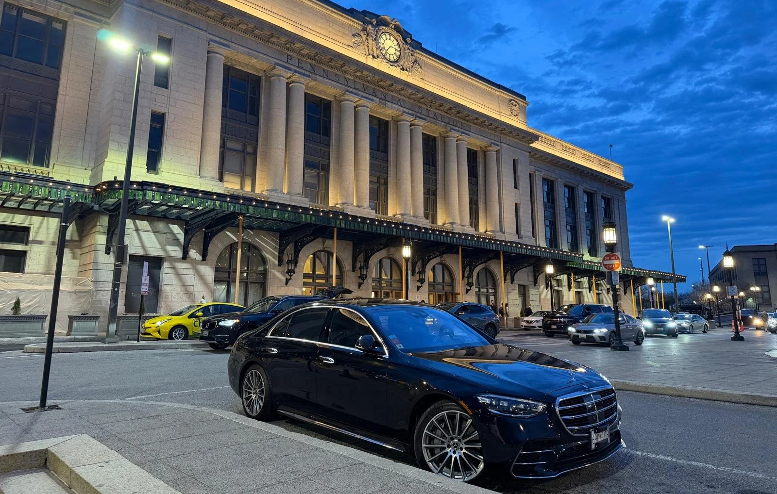 Luxury black sedan parked outside a historic station for point to point service