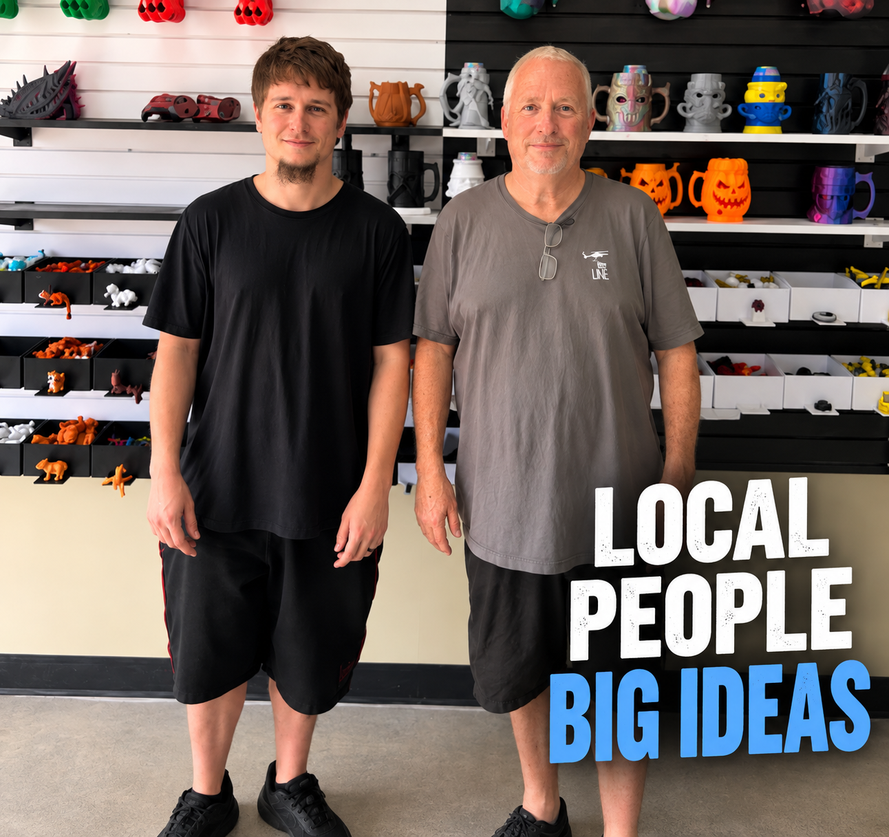Two men standing side by side in front of shelves filled with colorful merchandise, including mugs and small figurines, in a store. The older man on the right wears a gray t-shirt with glasses hanging on his collar, and the younger man on the left wears a black t-shirt and black shorts. Overlaid text reads "LOCAL PEOPLE BIG IDEAS."