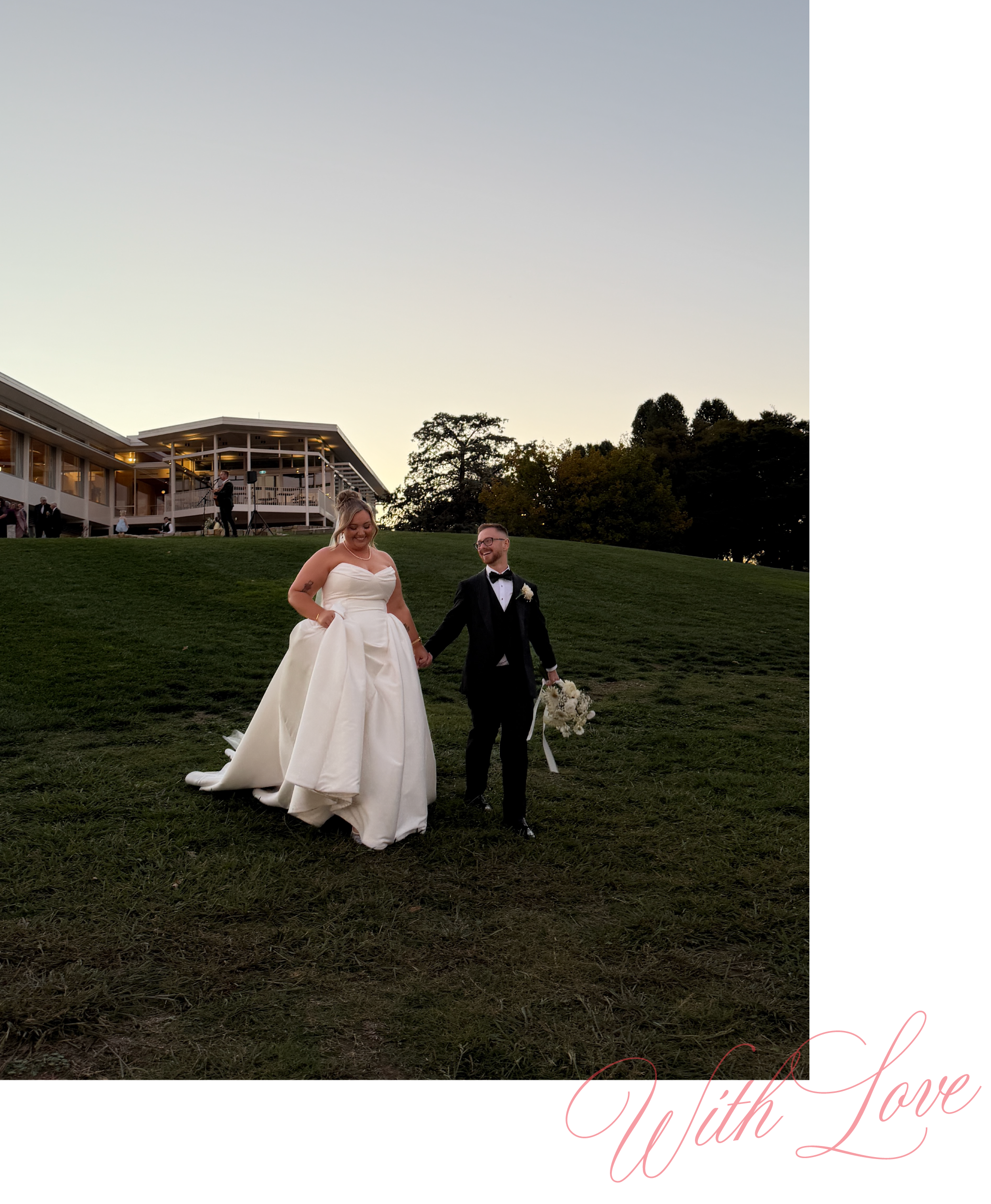 A bride and groom walking hand in hand on a grassy hill during sunset at a wedding. The bride is wearing a white strapless wedding gown and the groom is dressed in a black tuxedo. They are smiling and holding a bouquet of flowers.