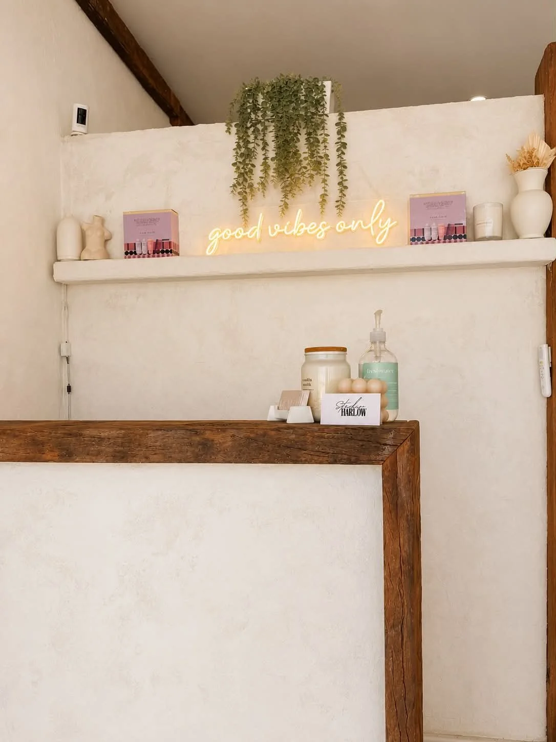 Interior details at Kara's Hair Chair in Belmont NSW, featuring the good vibes only sign, plants, candles and salon products inside the boutique salon space.