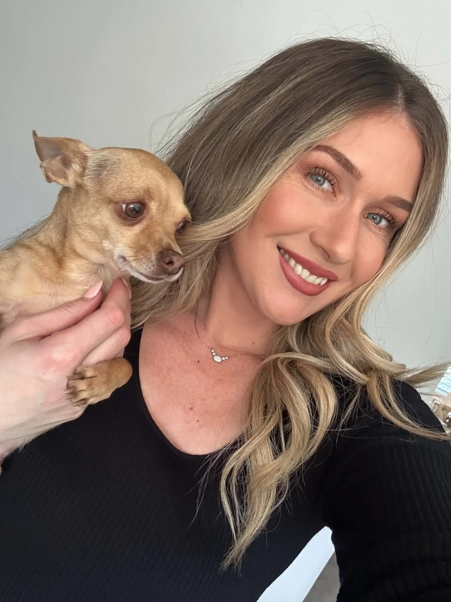 Kara, owner and hairdresser behind Kara's Hair Chair in Belmont NSW, with her Chihuahua Huxley.