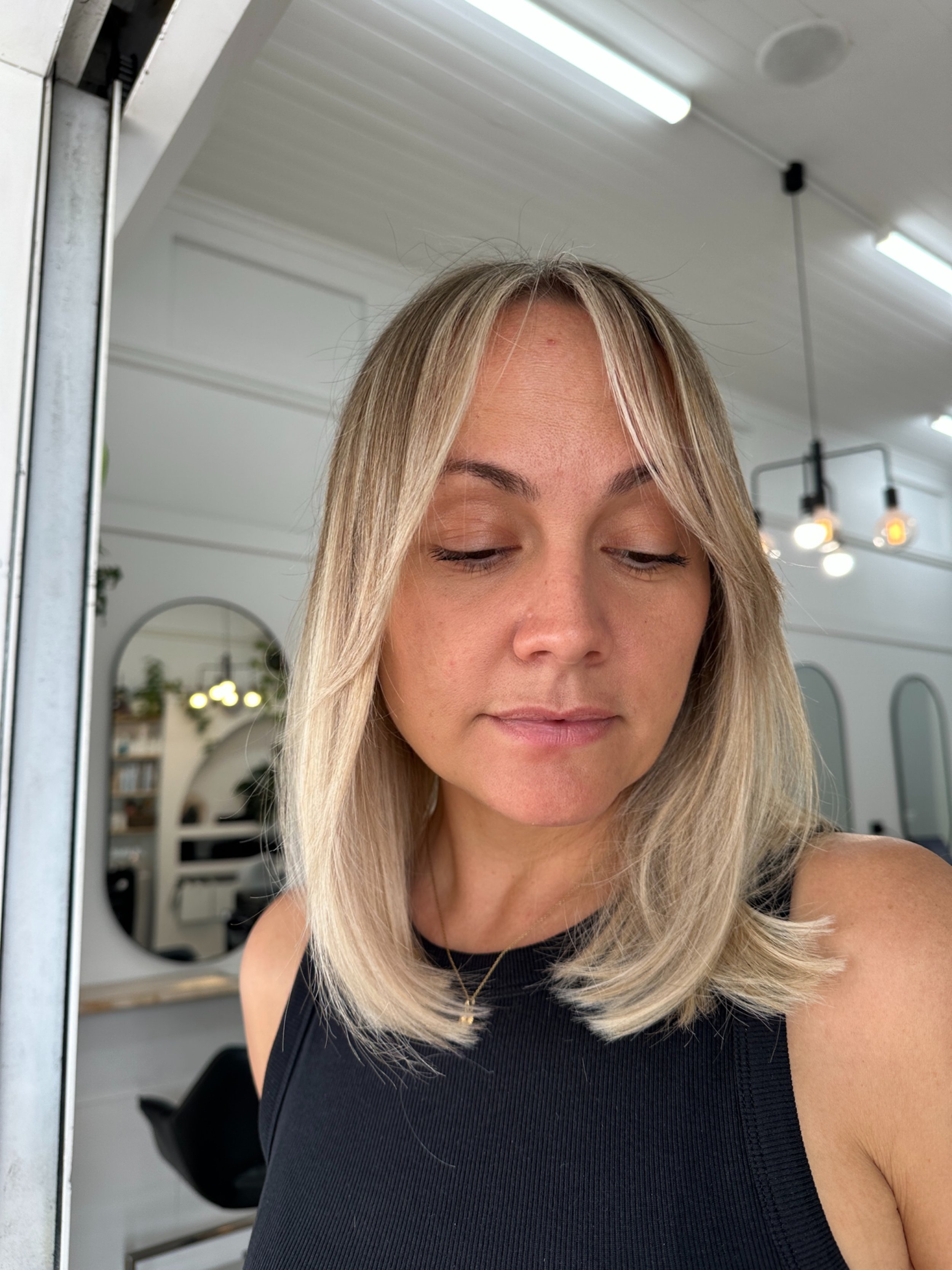 Dimensional lived in blonde with soft face framing and natural depth and bright ends. Healthy hair created by hairdresser Kara's Hair Chair in Belmont NSW.