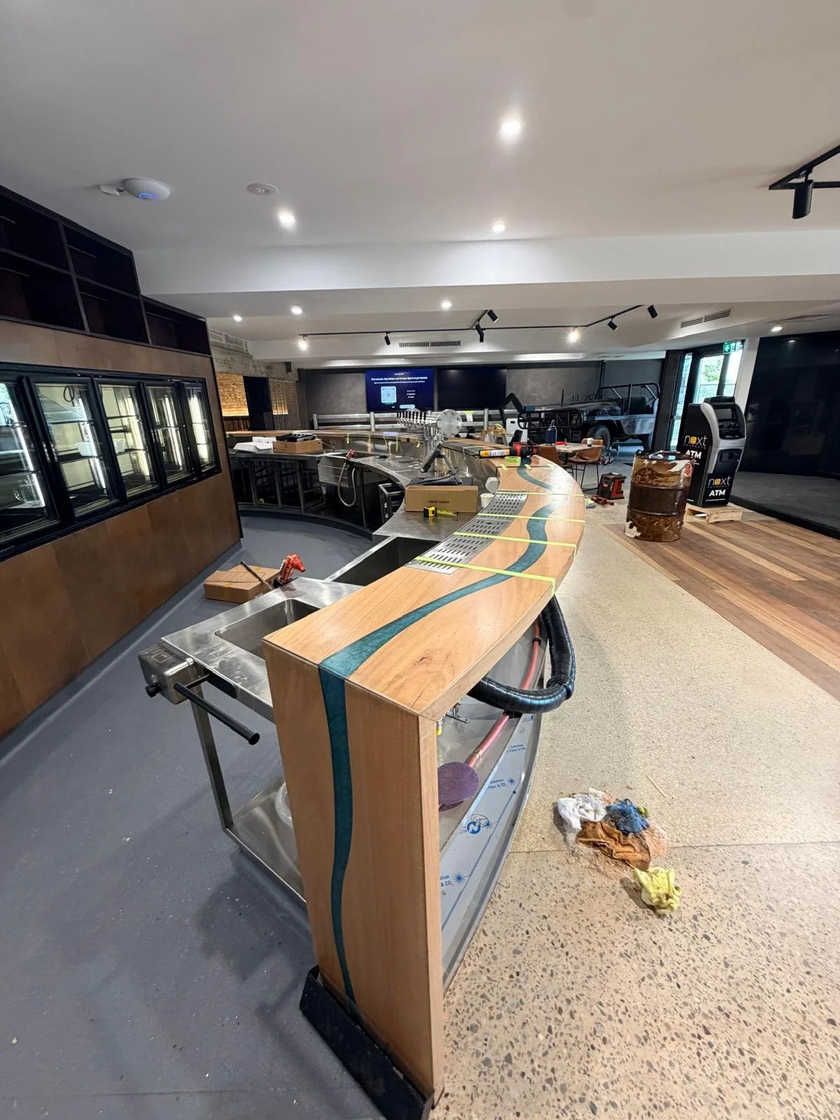 The curved Bluehole bar during installation on site, with the timber bartop and blue resin river fitted around the bar counter.
