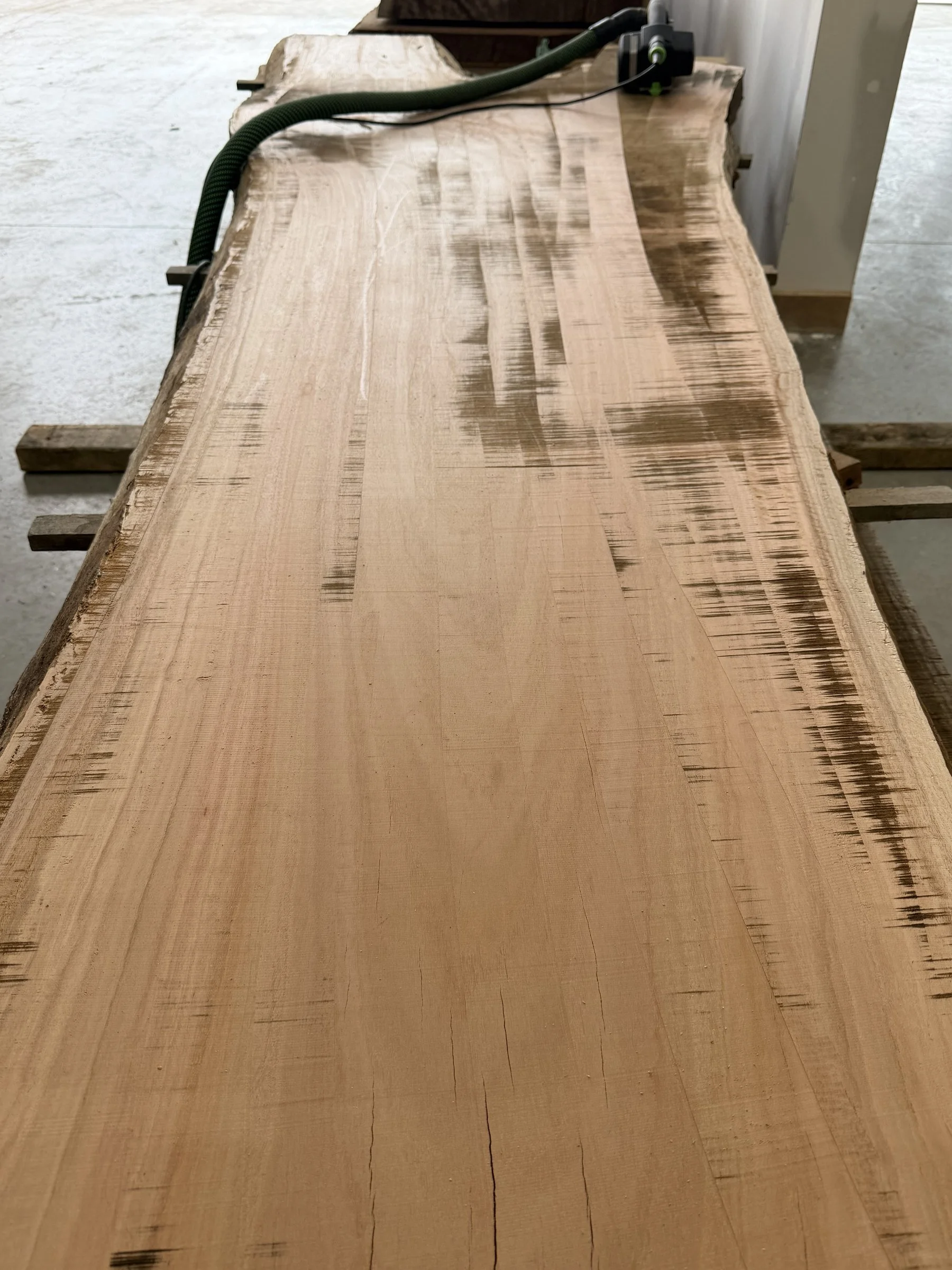 Step 1: a raw, rough-sawn timber slab in the Finecraft workshop before it is machined into bartop sections.