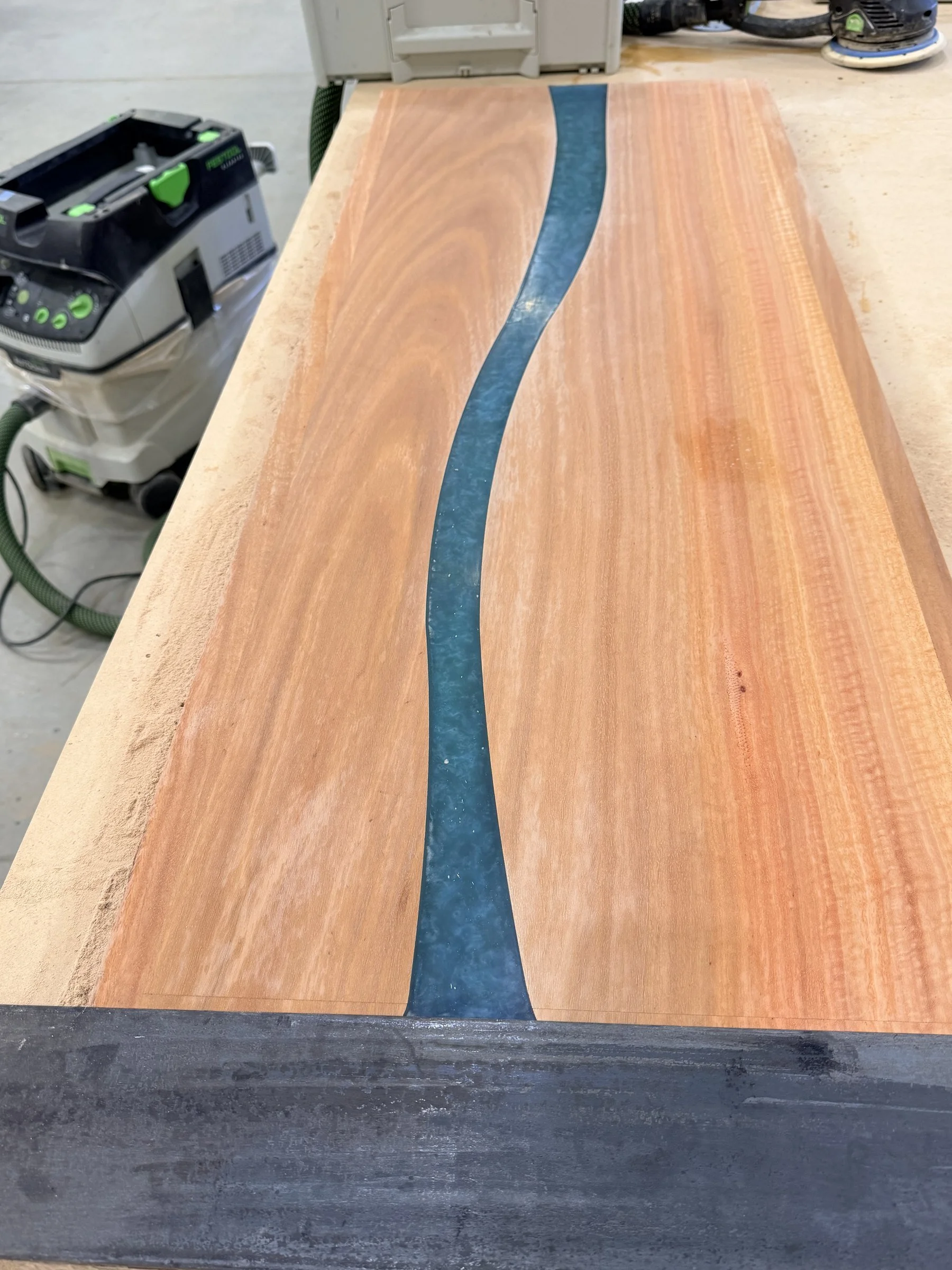 Step 5: close-up of the cured blue resin river winding through the sanded timber of a bartop section.