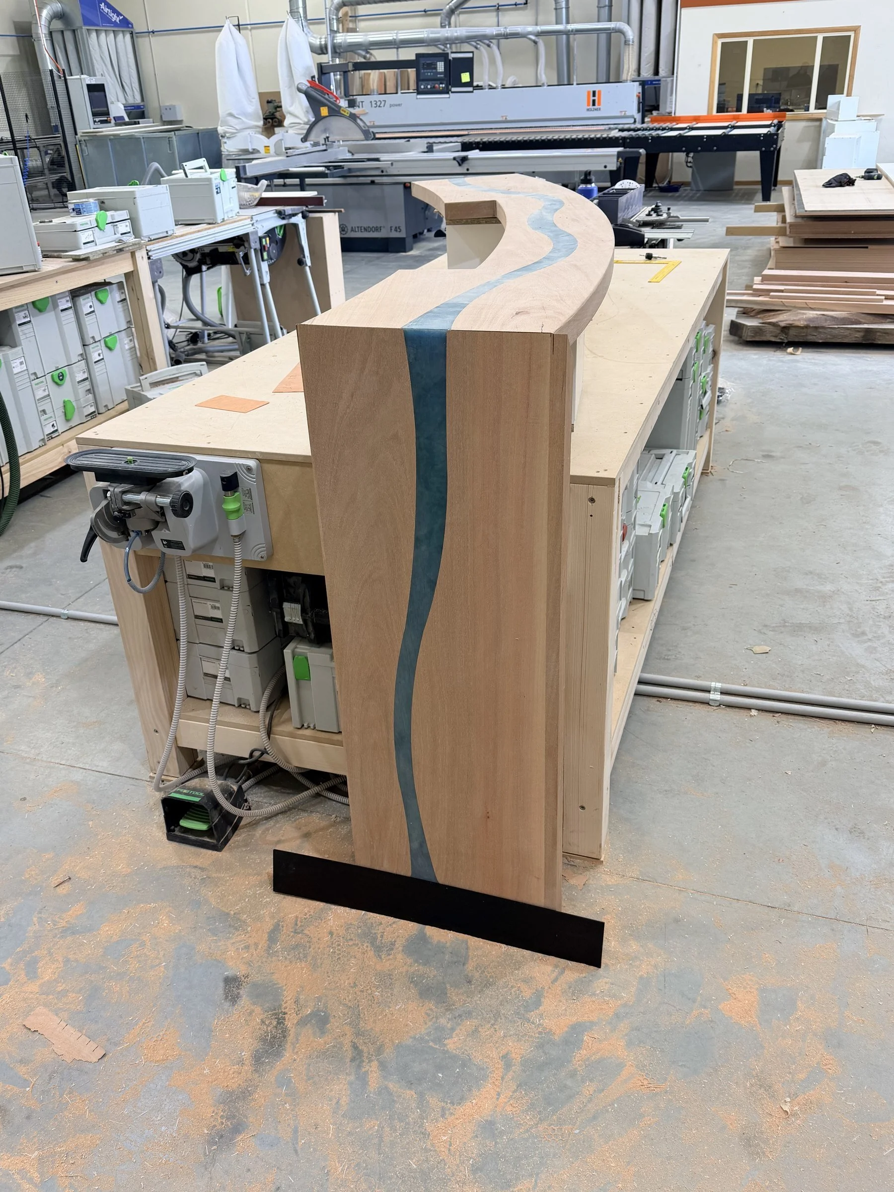 Step 6: a bartop end piece standing upright in the workshop, with the blue resin river continuing down its face.