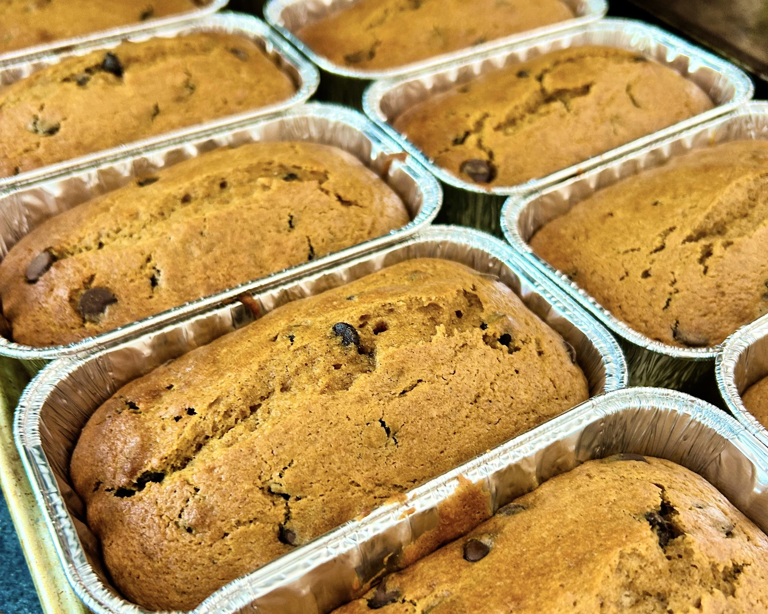 Close-up of multiple chocolate chip cookies in aluminum foil containers.