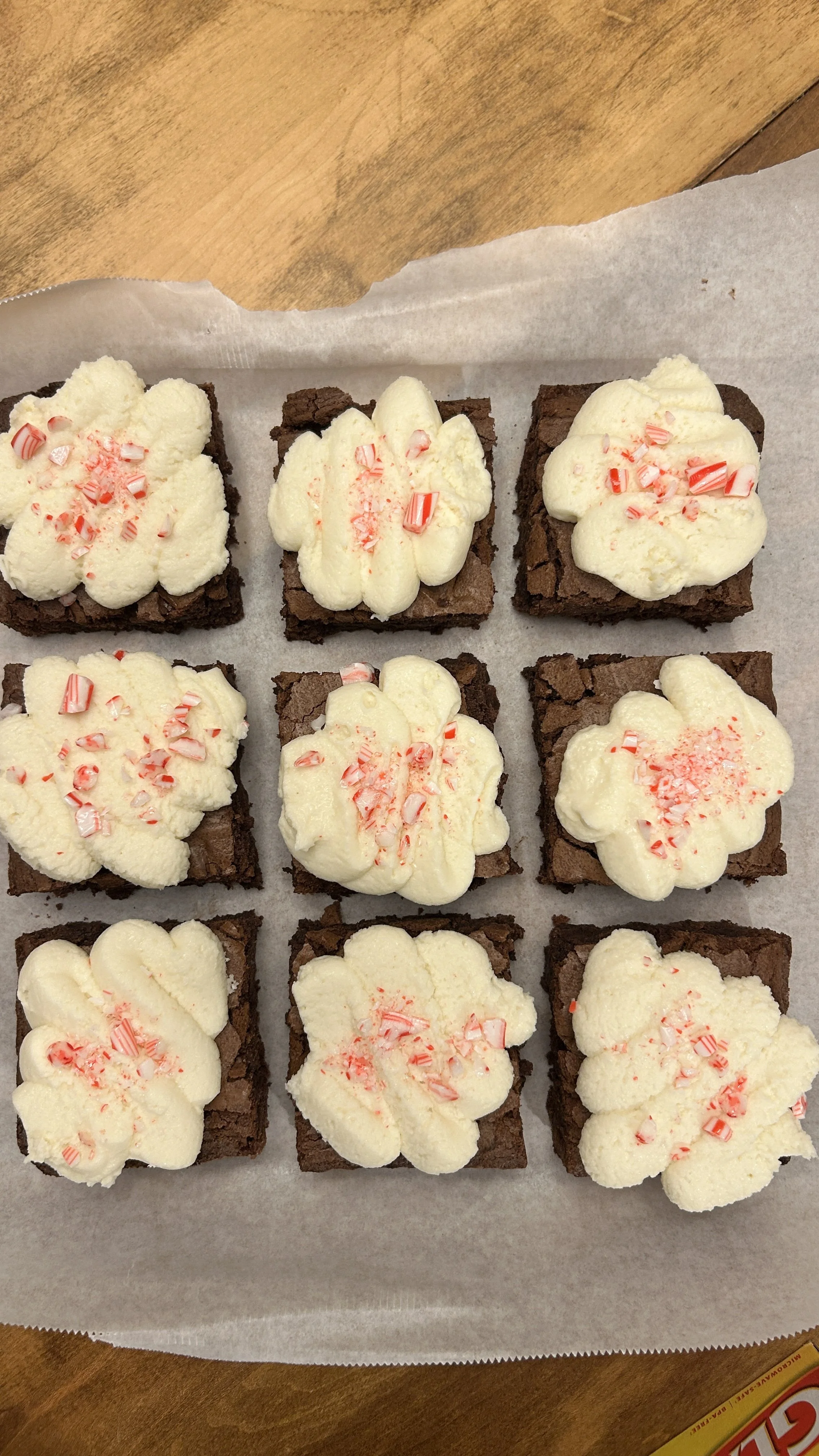 A tray of decorated brownie bars topped with vanilla frosting and crushed peppermint candies.