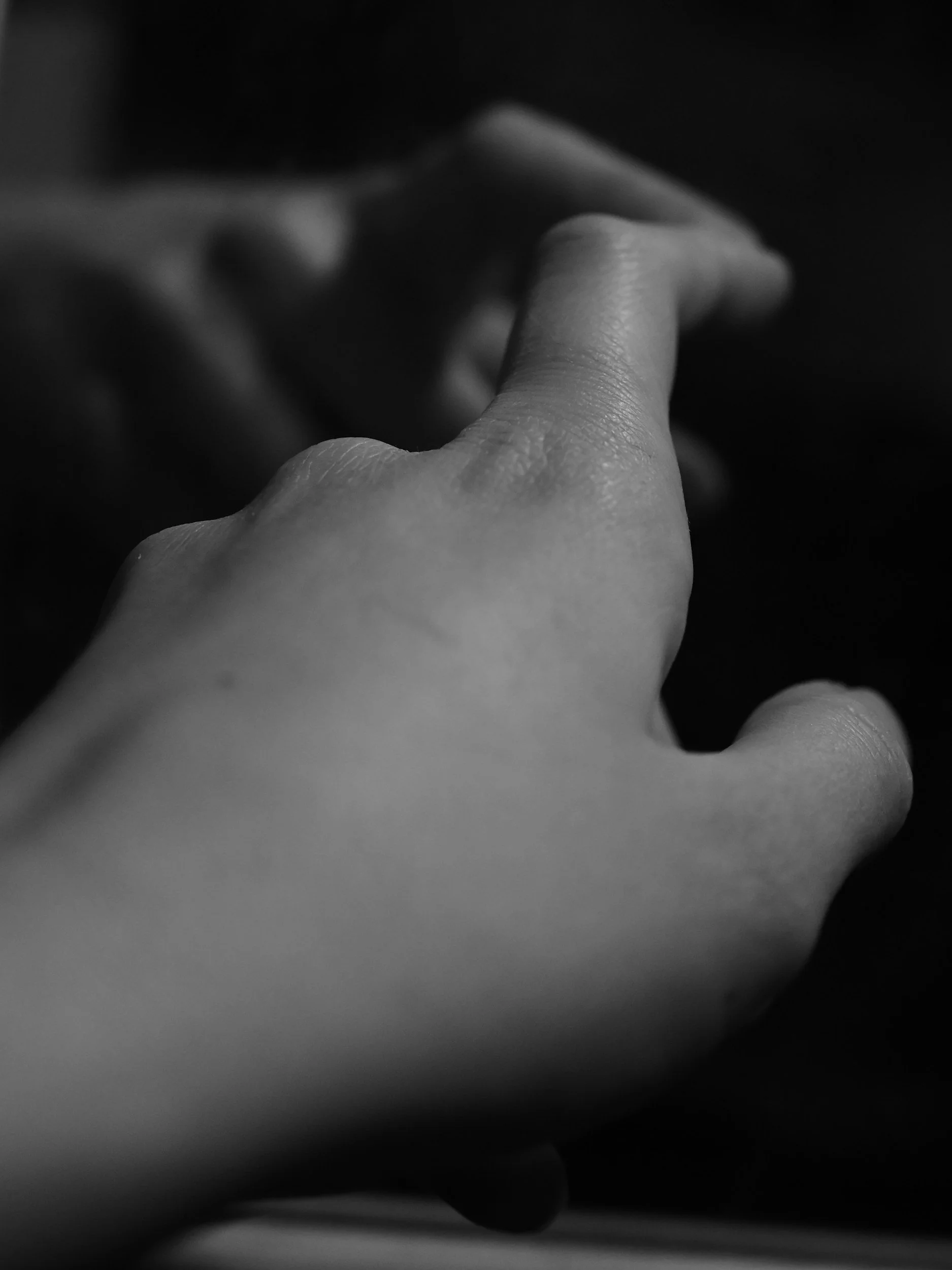 Close-up of a person's hand with fingers slightly bent, in black and white.