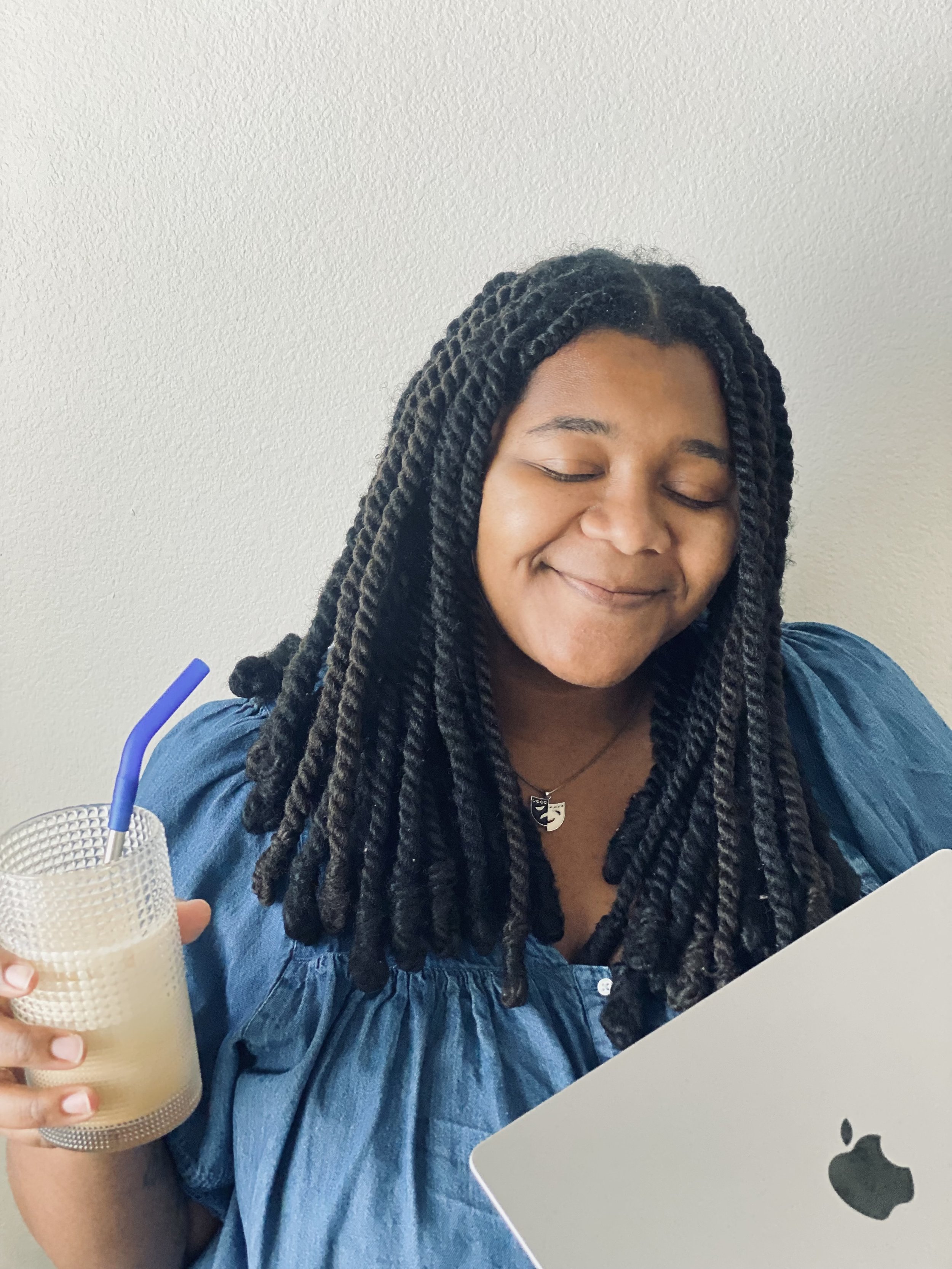 Trinity Perry holding an iced coffee while seated at her desk.