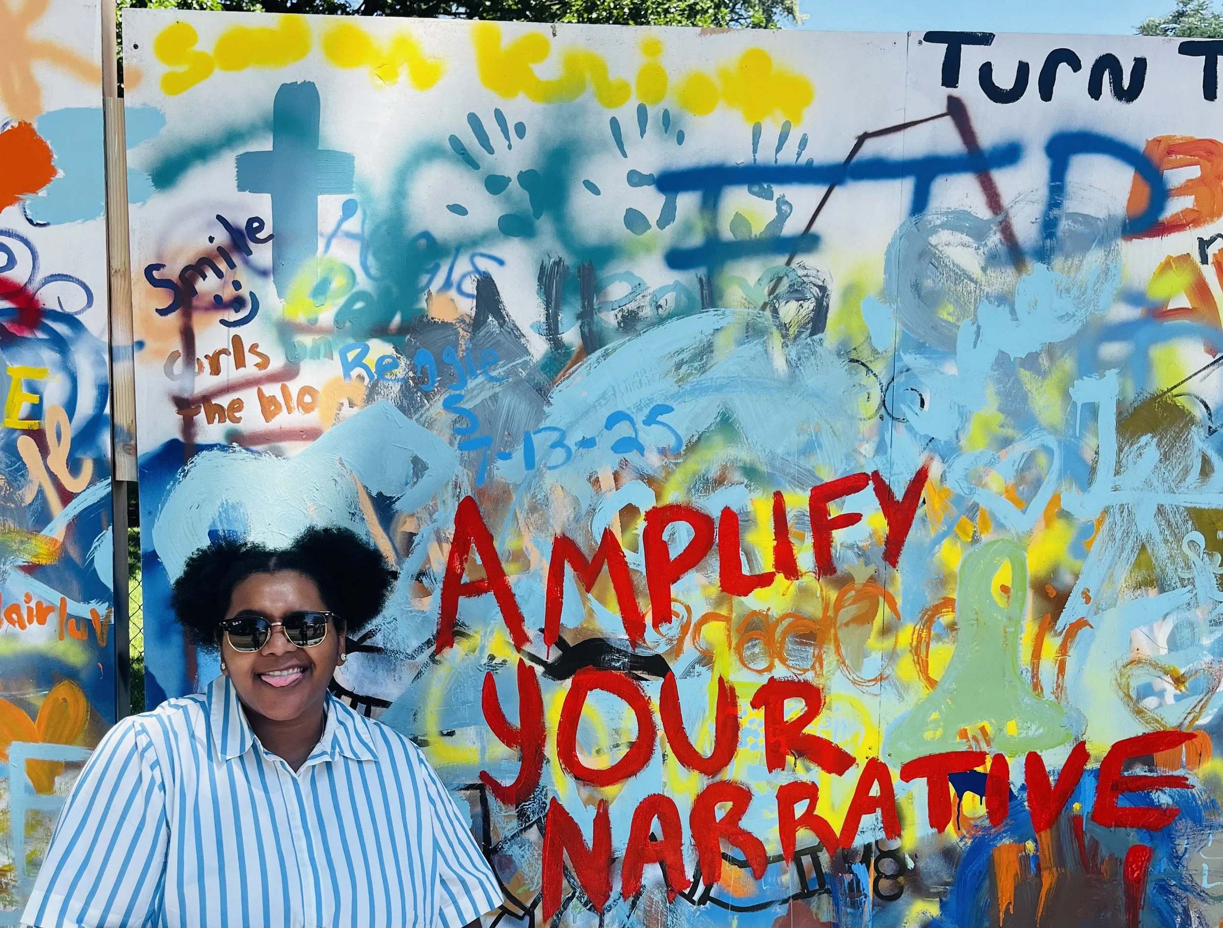 Trinity Perry creating a colorful “Amplify Your Narrative” mural.