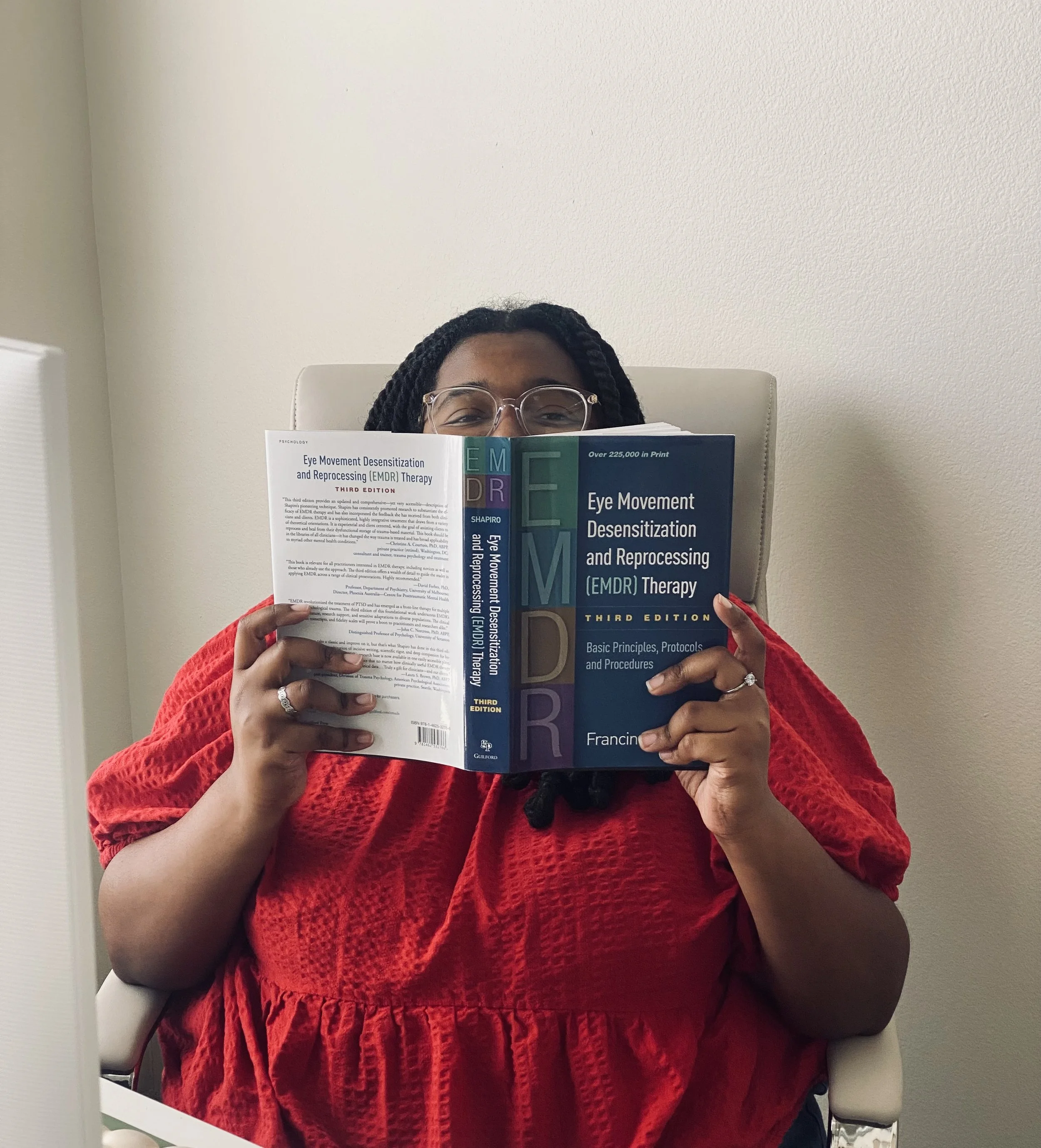 Trinity Perry holding a book about Eye Movement Desensitization and Reprocessing (EMDR) therapy.