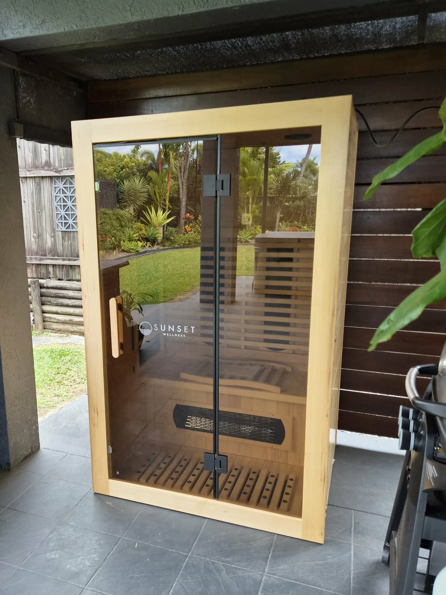 Wood and glass sauna with a view of a garden outside
