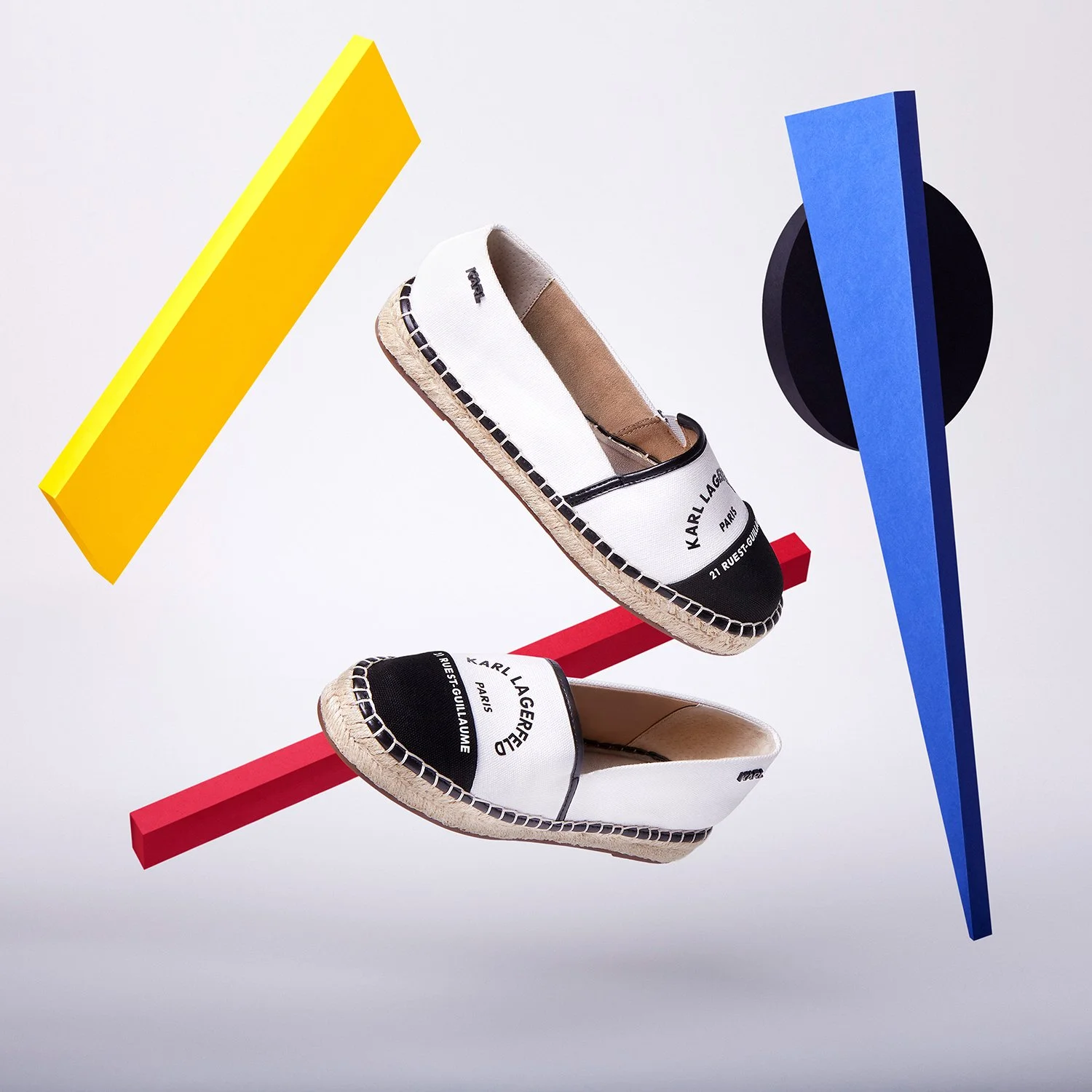 Chaussures de style espadrille avec logo Karl Lagerfeld, suspendues parmi des formes colorées abstraites.