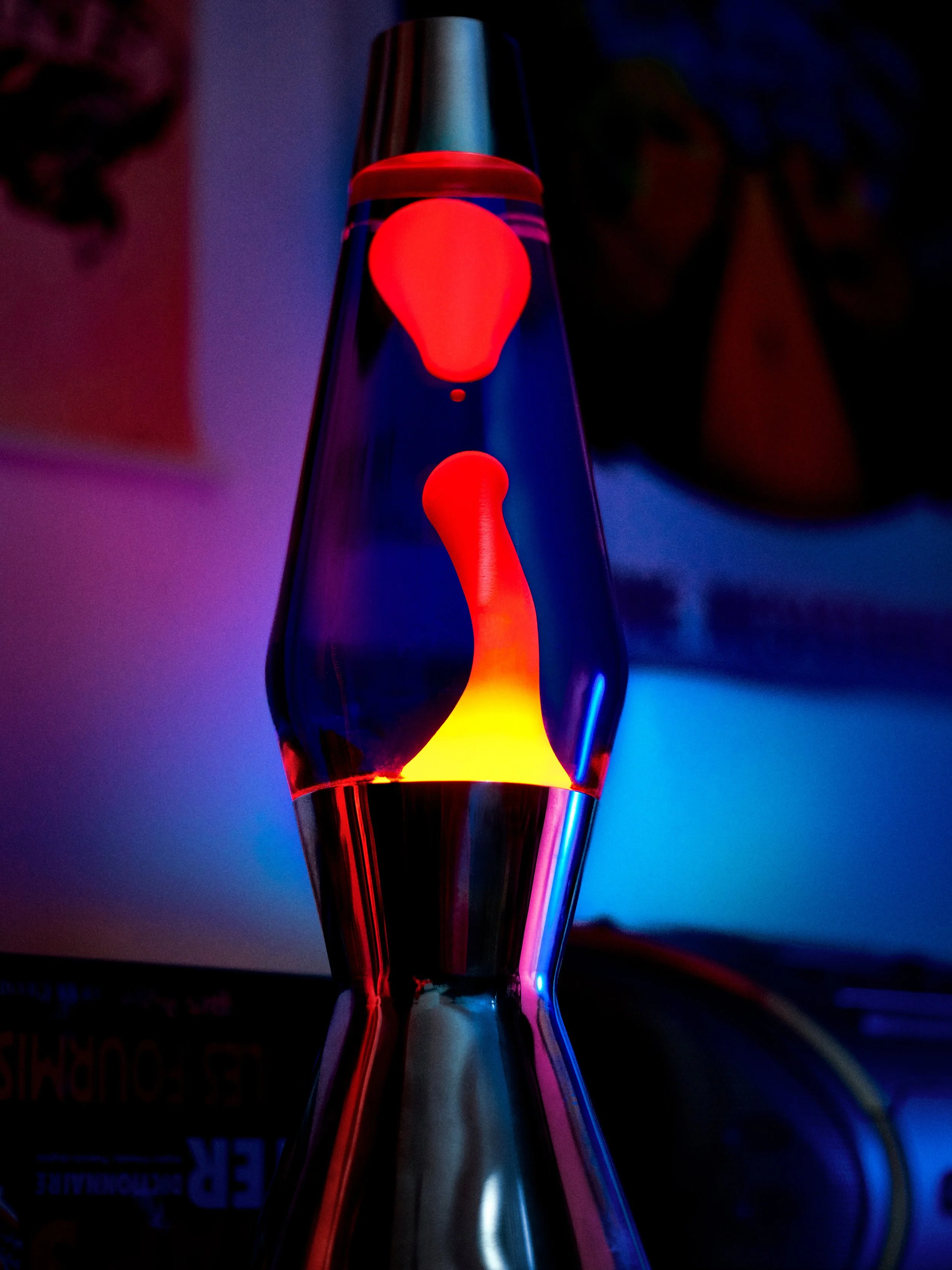 Une lampe de Lava orange avec une base métallique, éclairée dans l'obscurité.