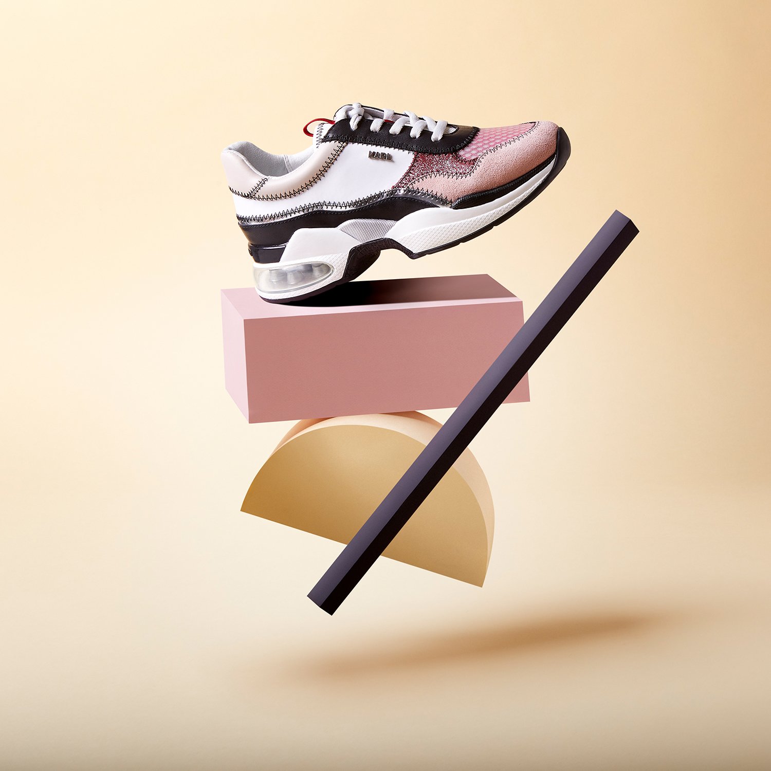 Une chaussure de sport moderne posée sur des formes géométriques colorées et des plans sur fond beige
