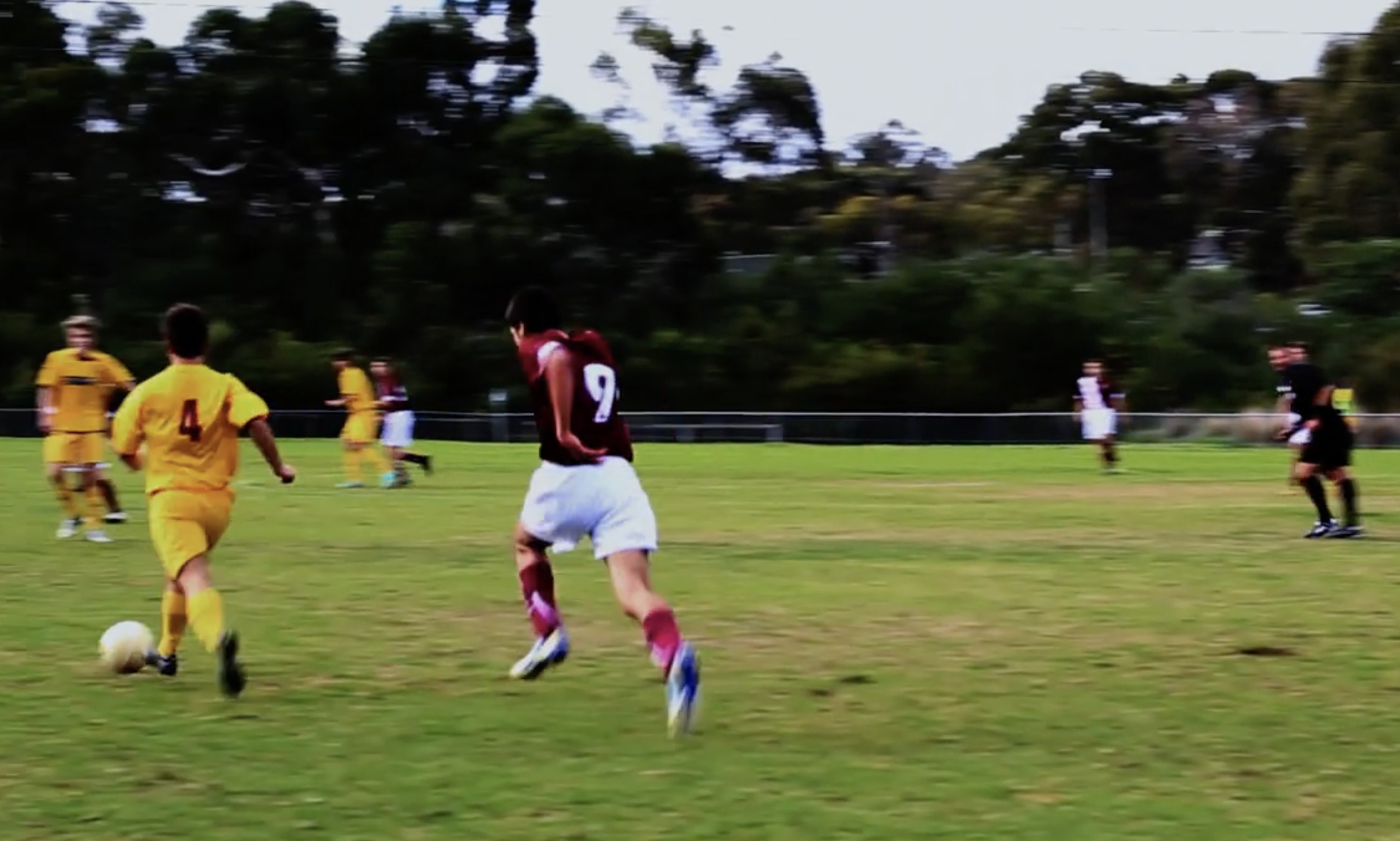 males run after a soccer ball on a soccer field