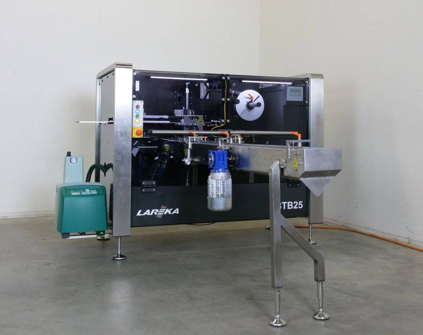 Automated machine used for chocolate packaging, labeled 'LAREKA' and 'BTB25', with a control panel, and various mechanical parts, positioned on a clean concrete floor against a plain white wall.