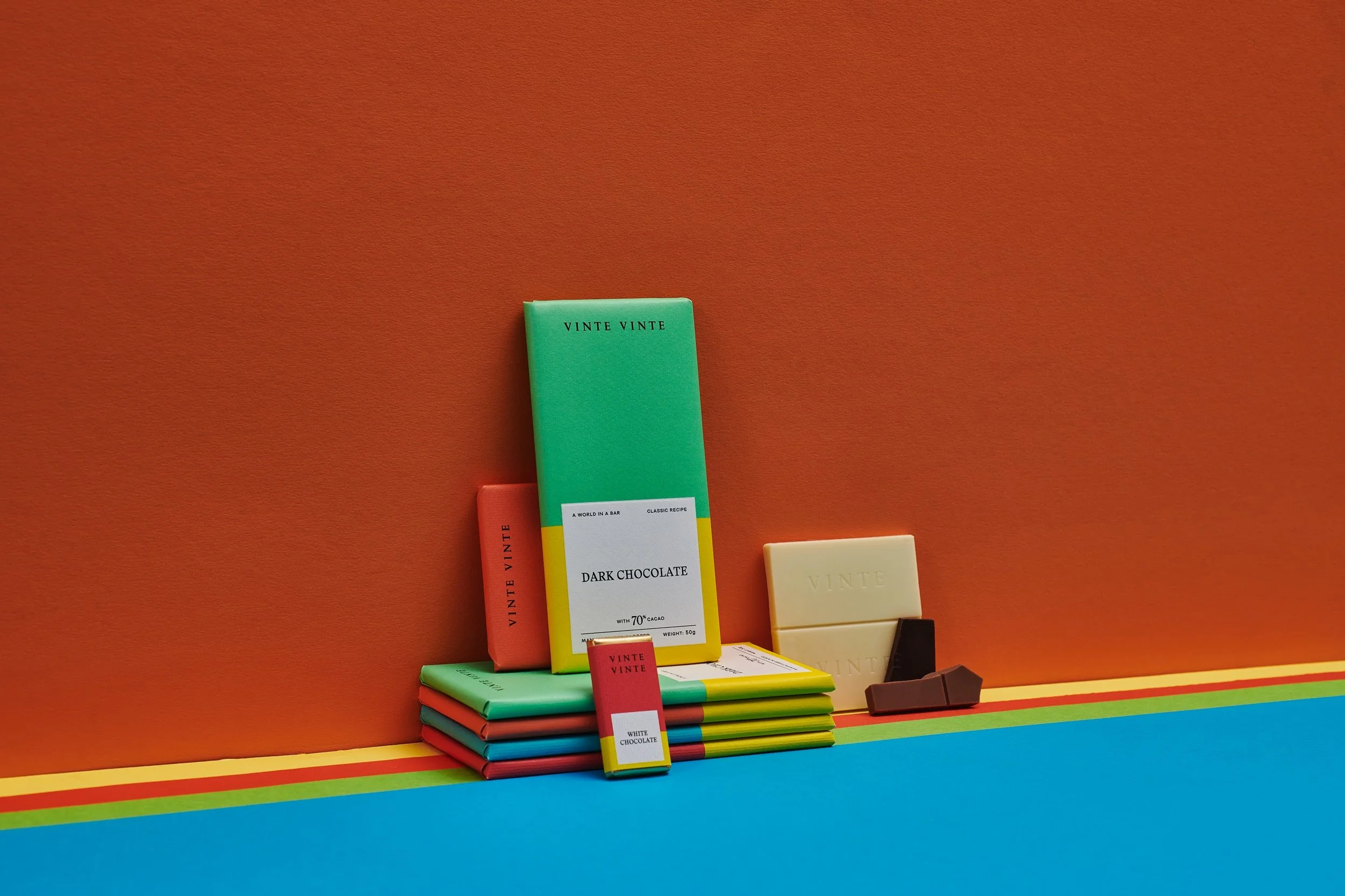 Colorful display of various chocolate bars from VINTE VINTE and packaging against a vibrant background.