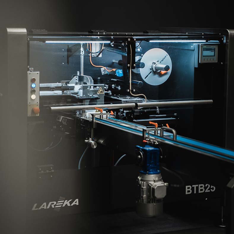A chocolate packaging machine with the brand name 'LAREKA' and model 'BTB25', used for chocolate bars packaging, with various mechanical and electronic components visible inside.
