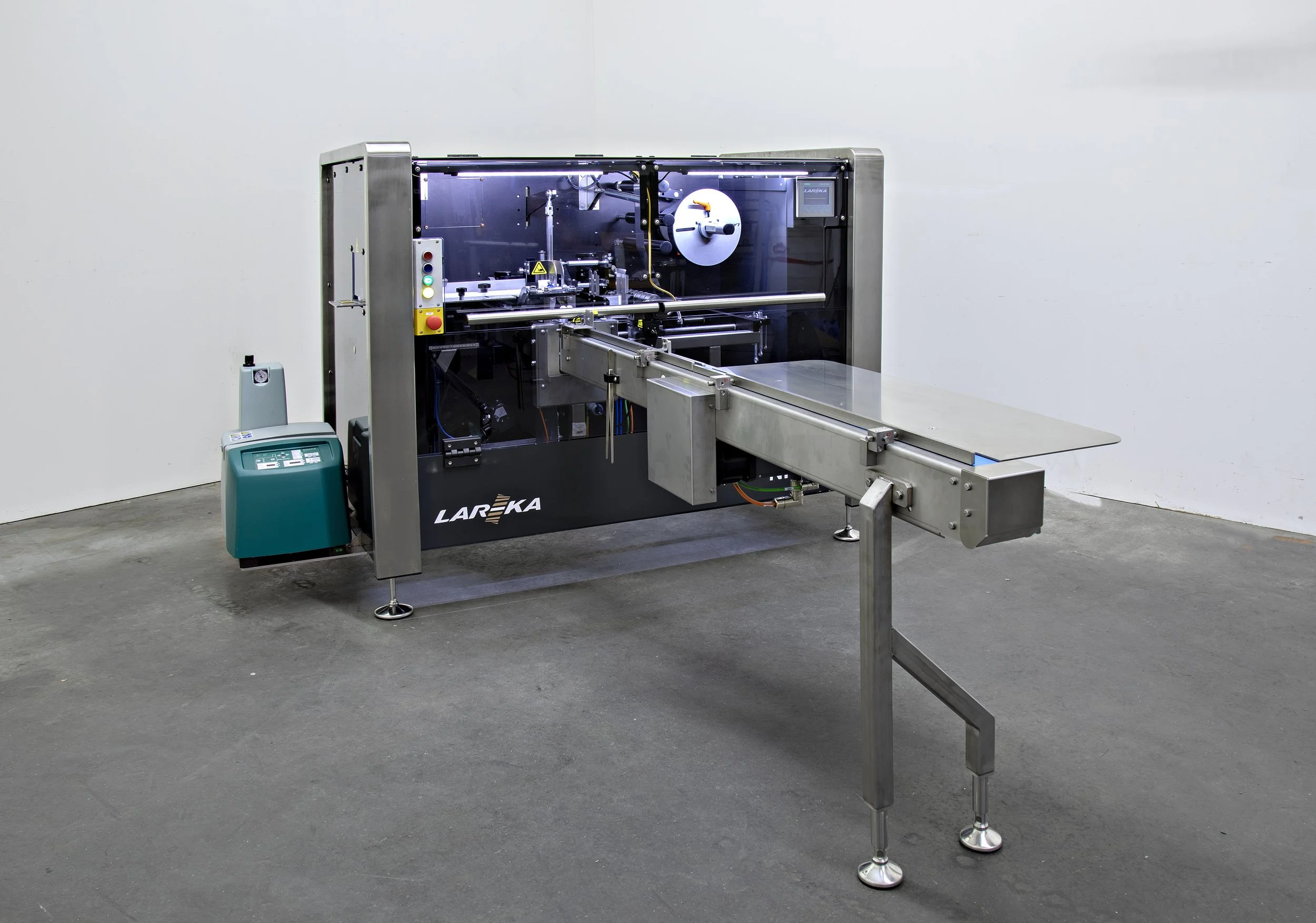 NP60 Chocolate packaging machine with control panel andlong infeed conveyor belt in an empty room, used for wrapping Napolitains and small chocolate bars in premium packaging styles.